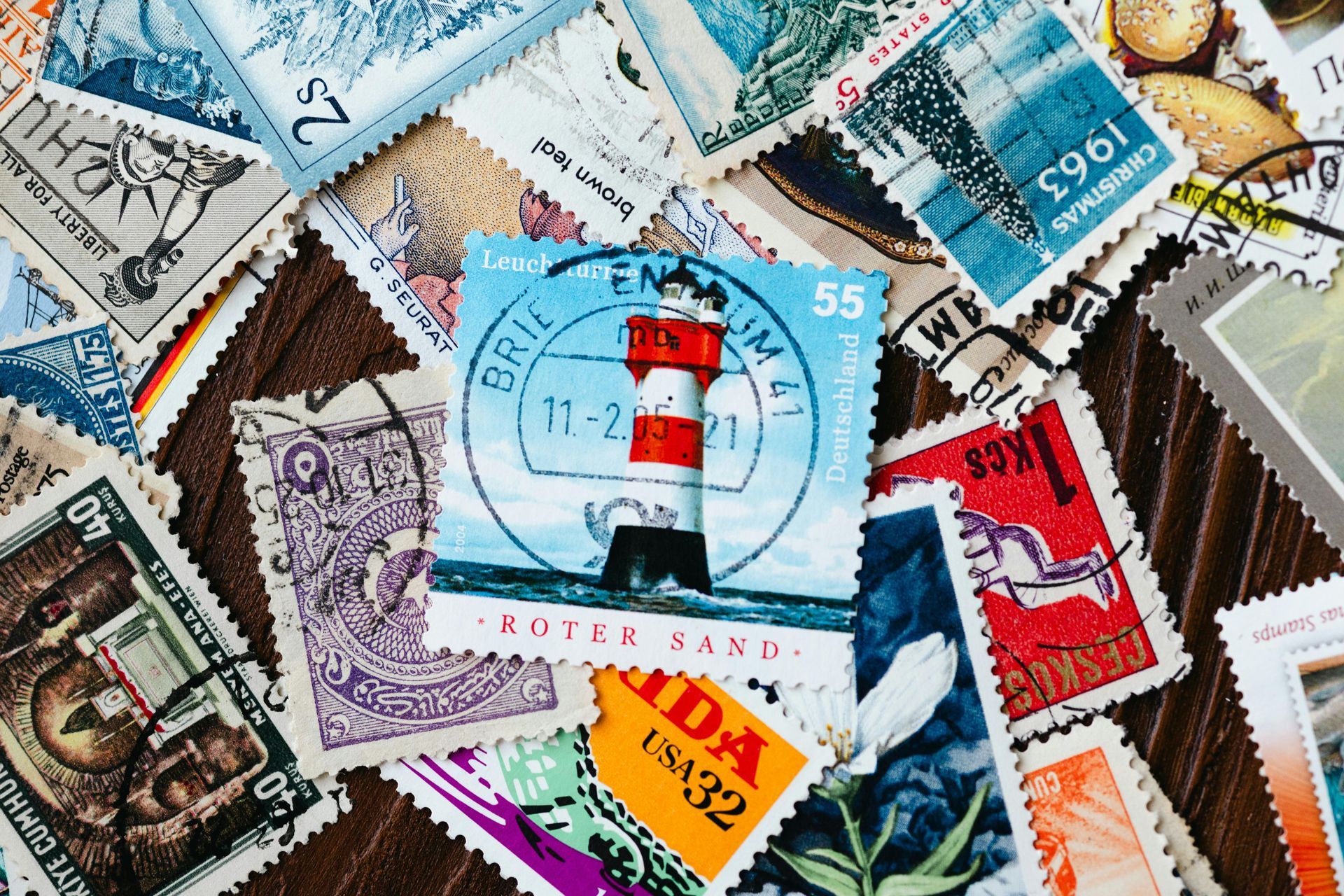 Pile of colorful postage stamps, including ones with lighthouses and flags.