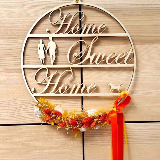 An einer Holzwand hängt ein Schild mit der Aufschrift „Home Sweet Home“.