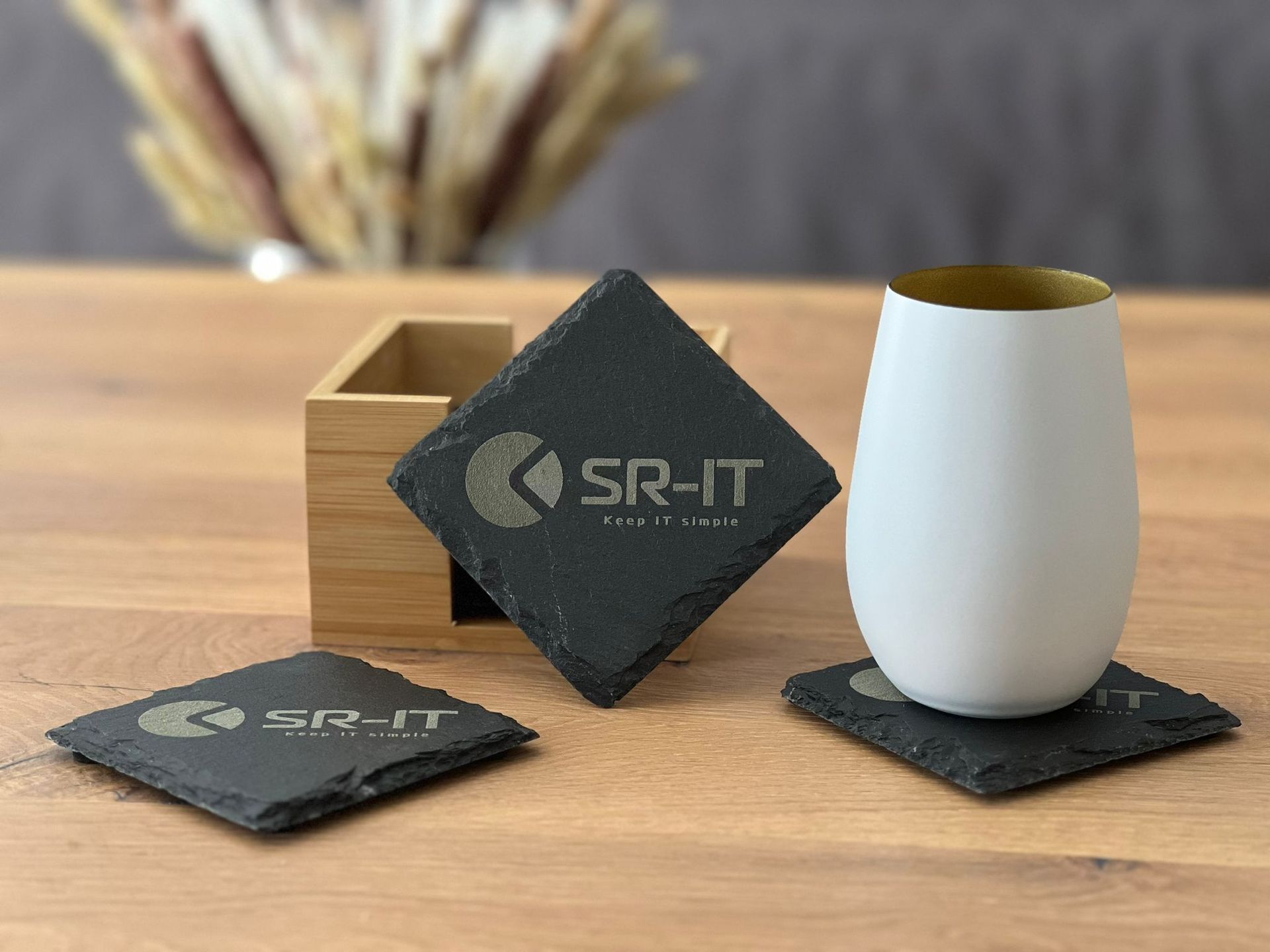 Ein Satz Schieferuntersetzer und ein Glas auf einem Holztisch.