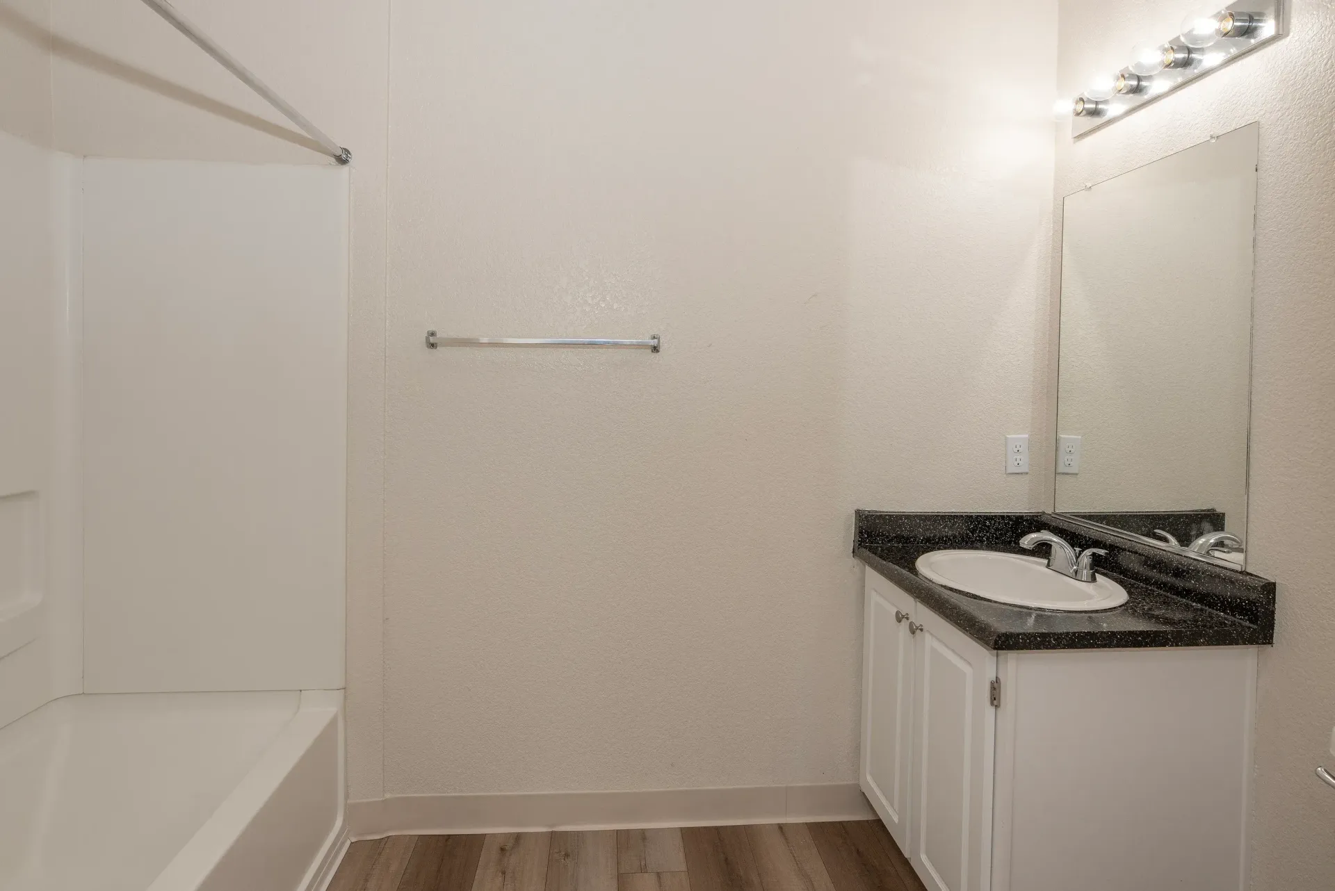 Bathroom vanity with sink, mirror, and tub/shower in an apartment.