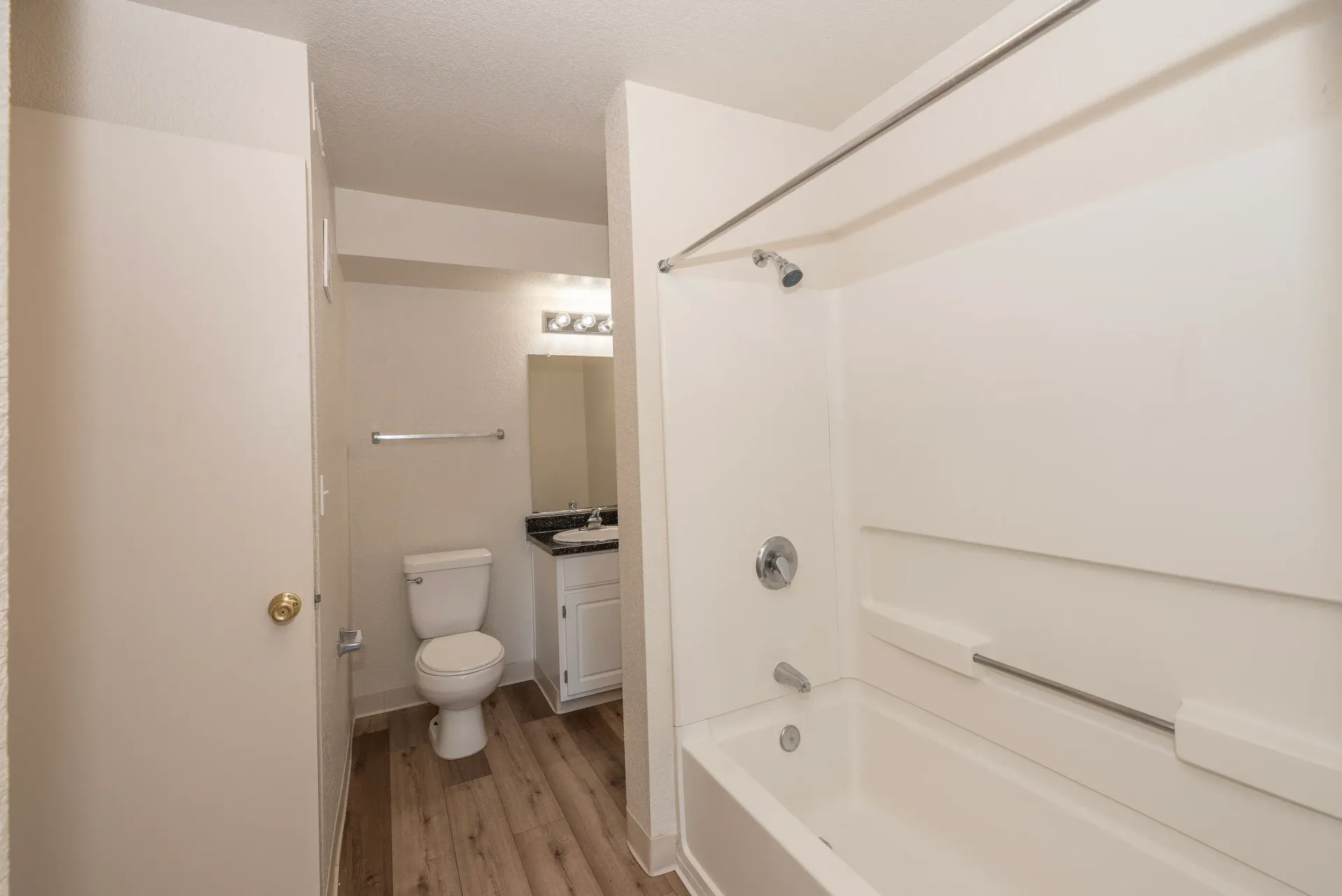 Bathroom in an apartment featuring a toilet, vanity with sink, and tub-shower.