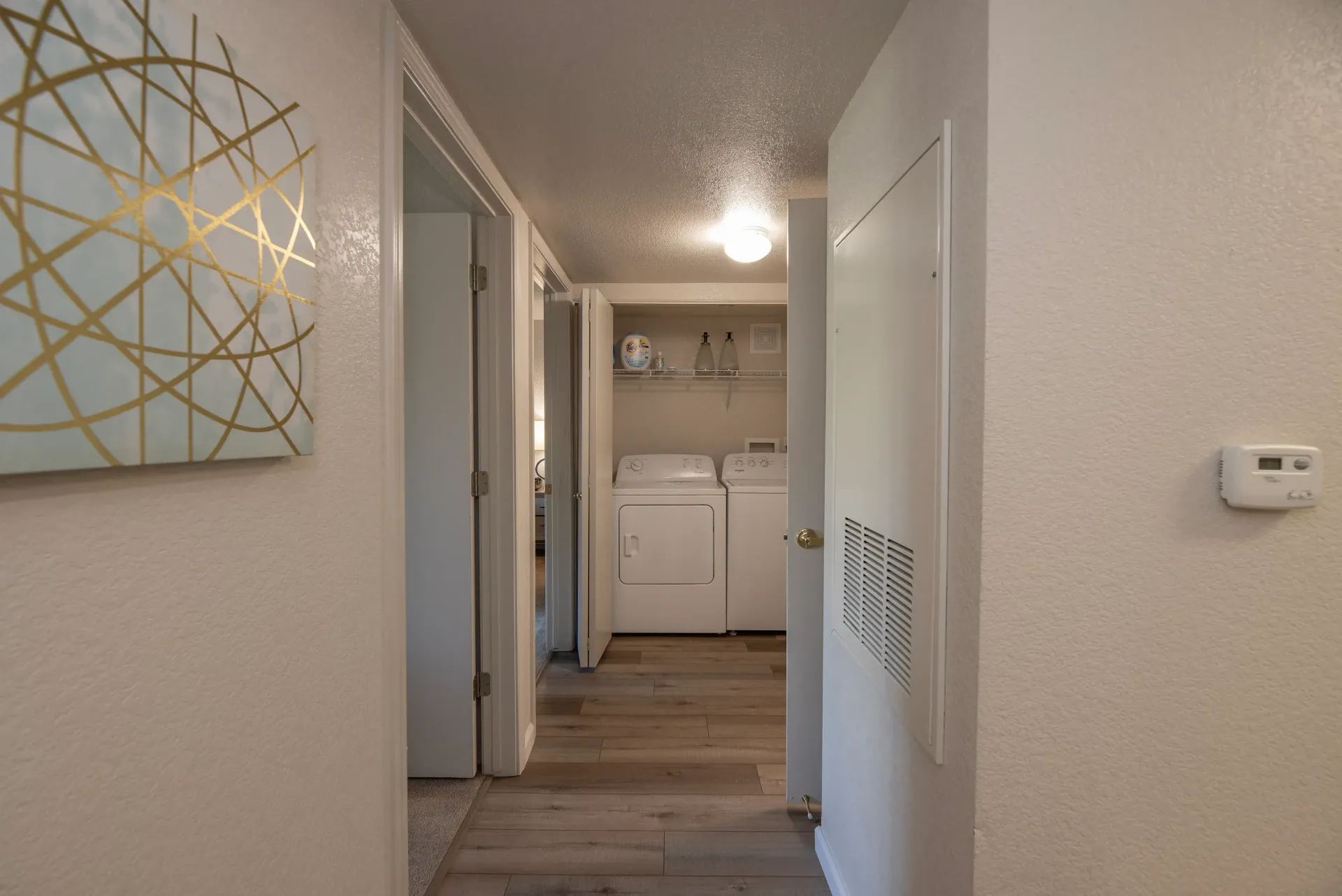 Hallway view of a laundry closet with side-by-side washer and dryer.