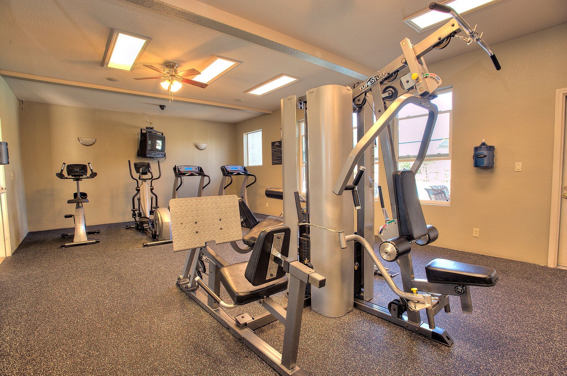 Indoor apartment fitness center with cardio machines and weight equipment.