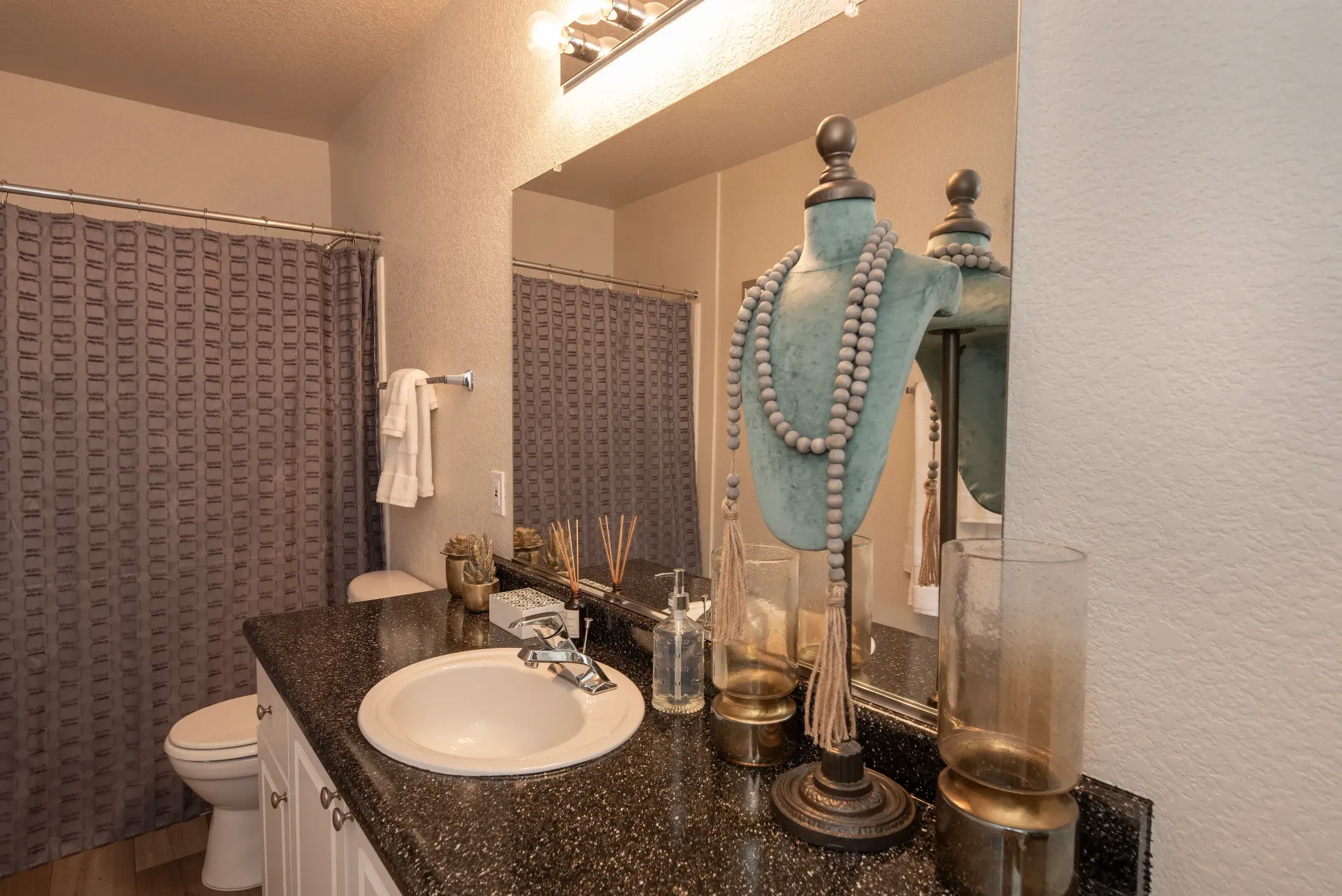 Bathroom vanity with sink, mirror, towel bar, shower curtain, and a bead necklace display.