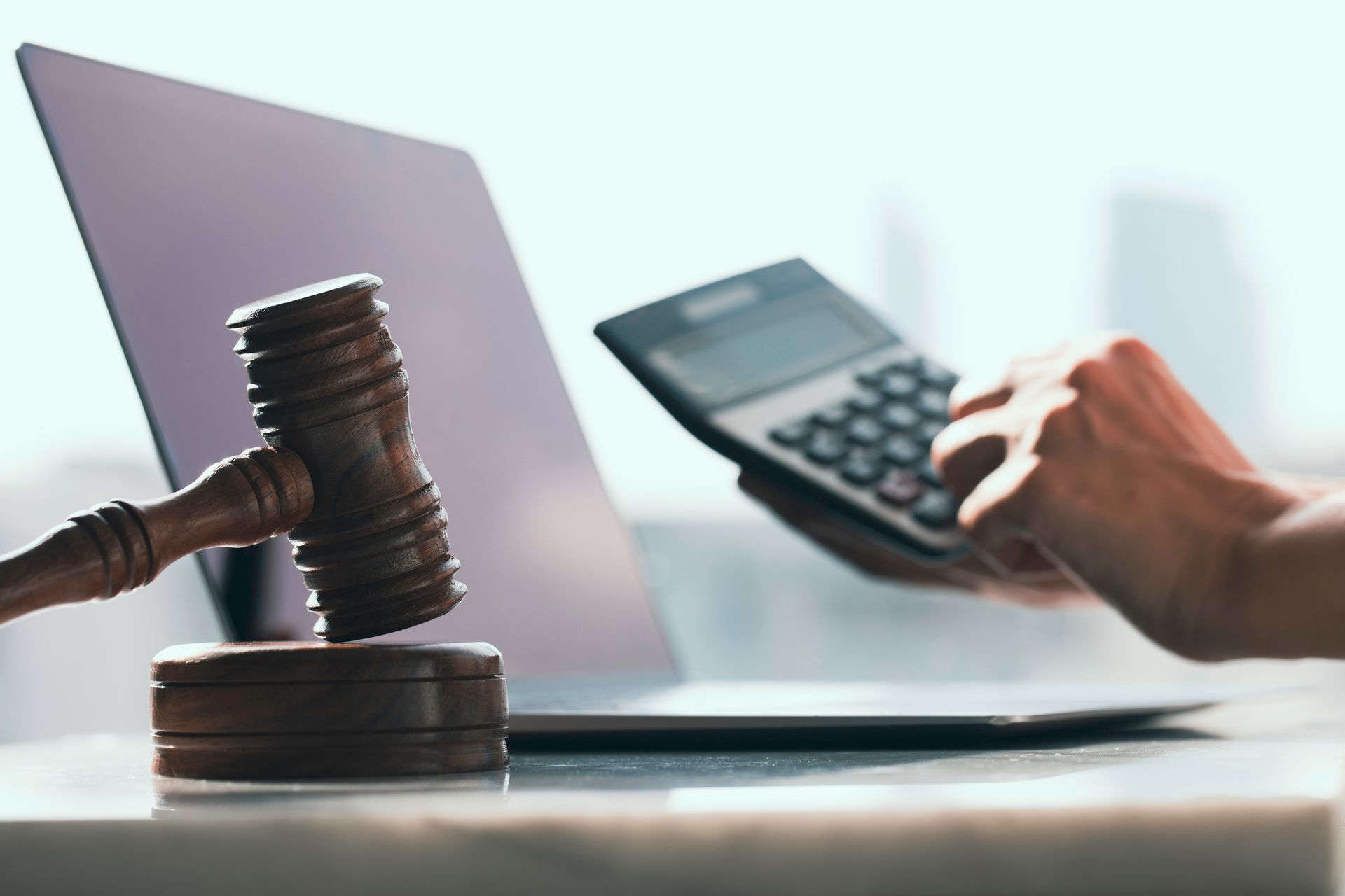 Bail bondsman working on a calculator and laptop with a wooden gavel next to it. Bail bondsman working on a calculator and laptop with a wooden gavel next to it.