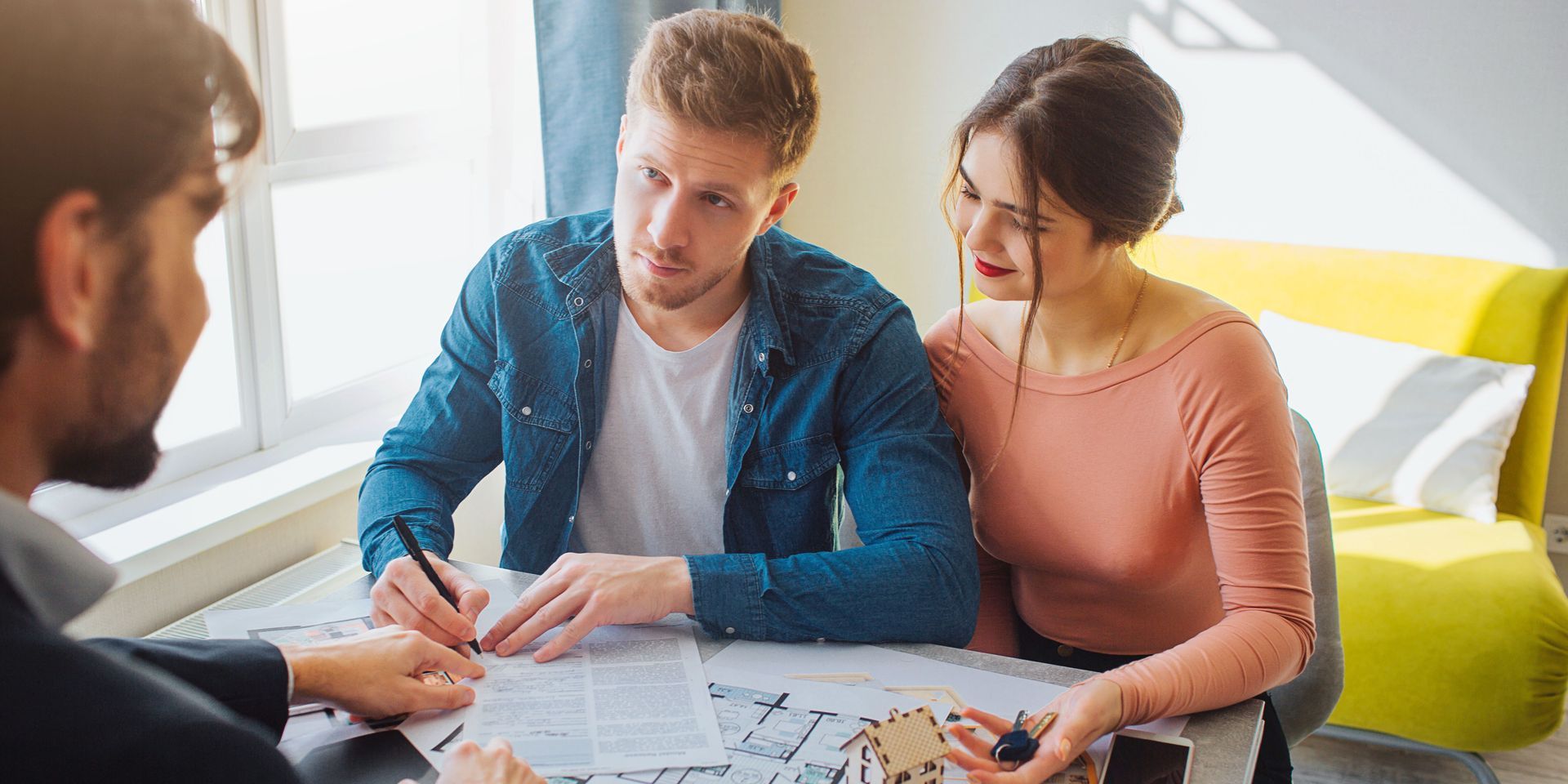 A man and a woman are sitting at a table looking at a blueprint.