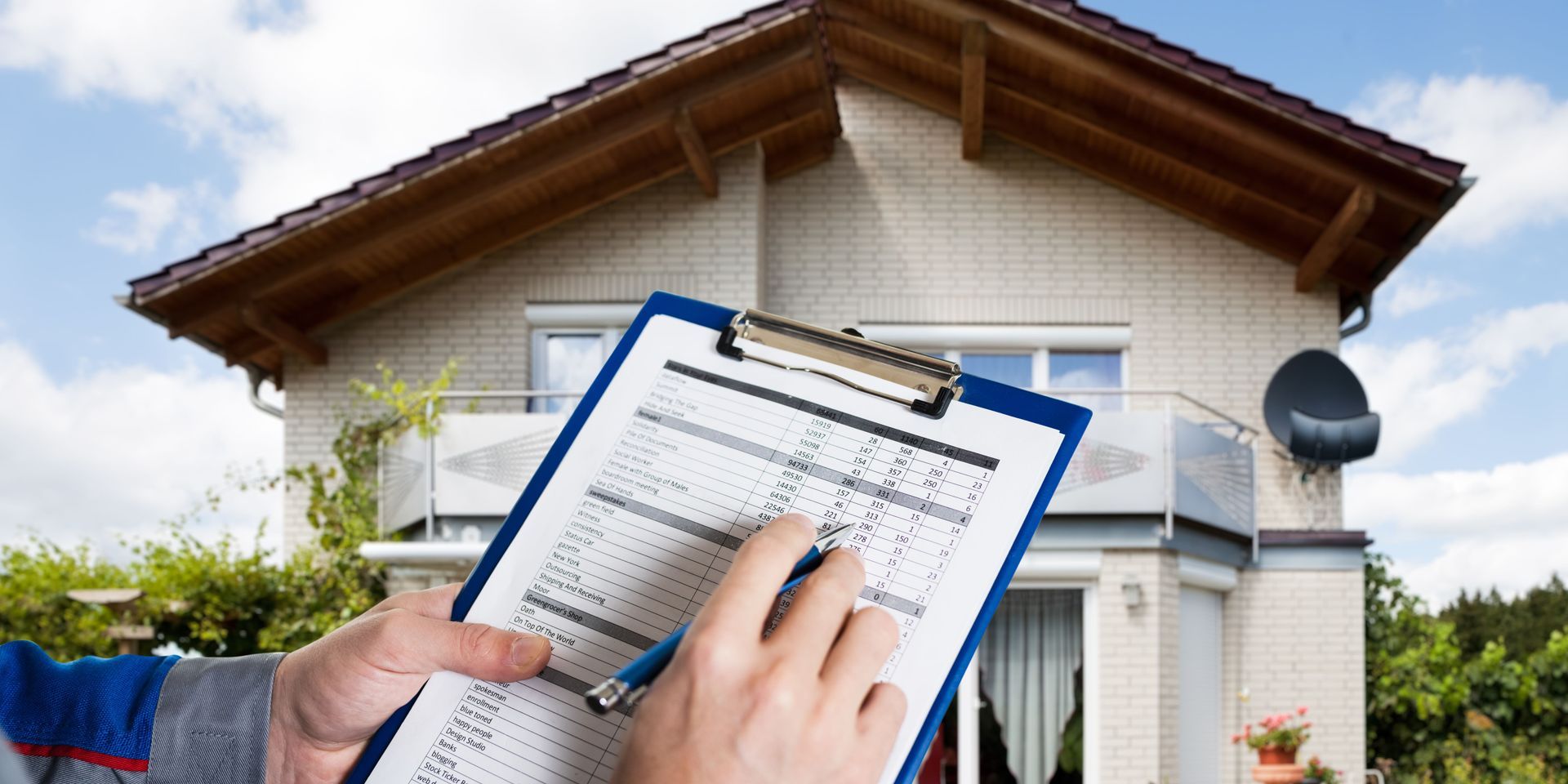 A person is holding a clipboard in front of a house.