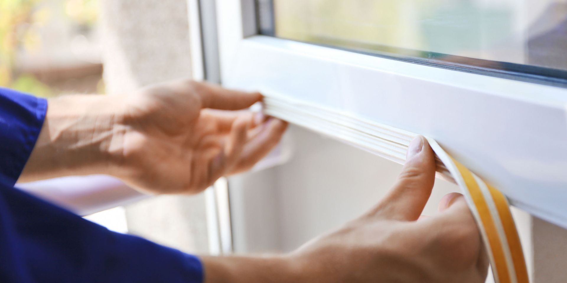 Person installing weather stripping on a window frame.