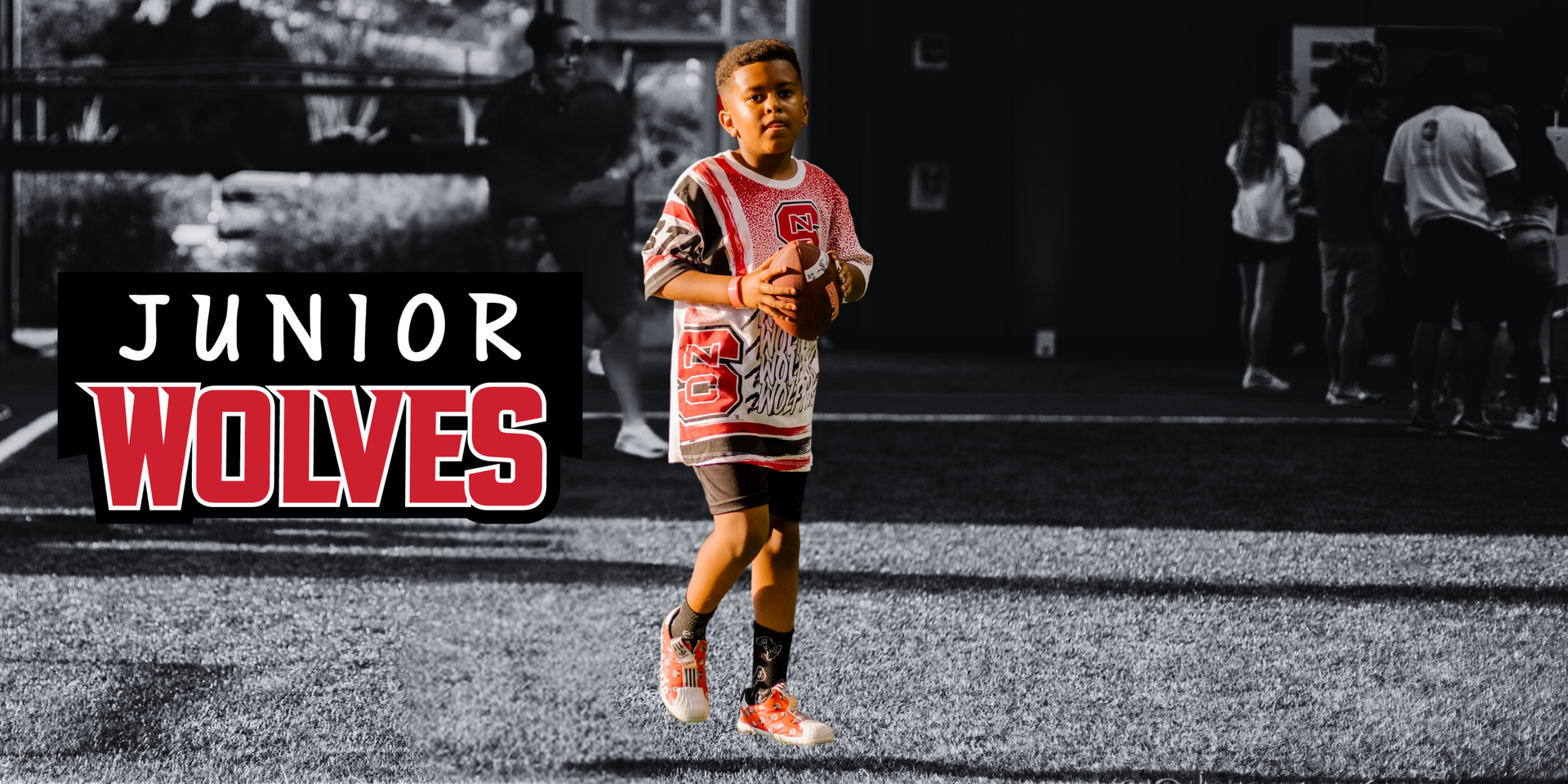 A young boy in a red and white jersey is running on a football field.