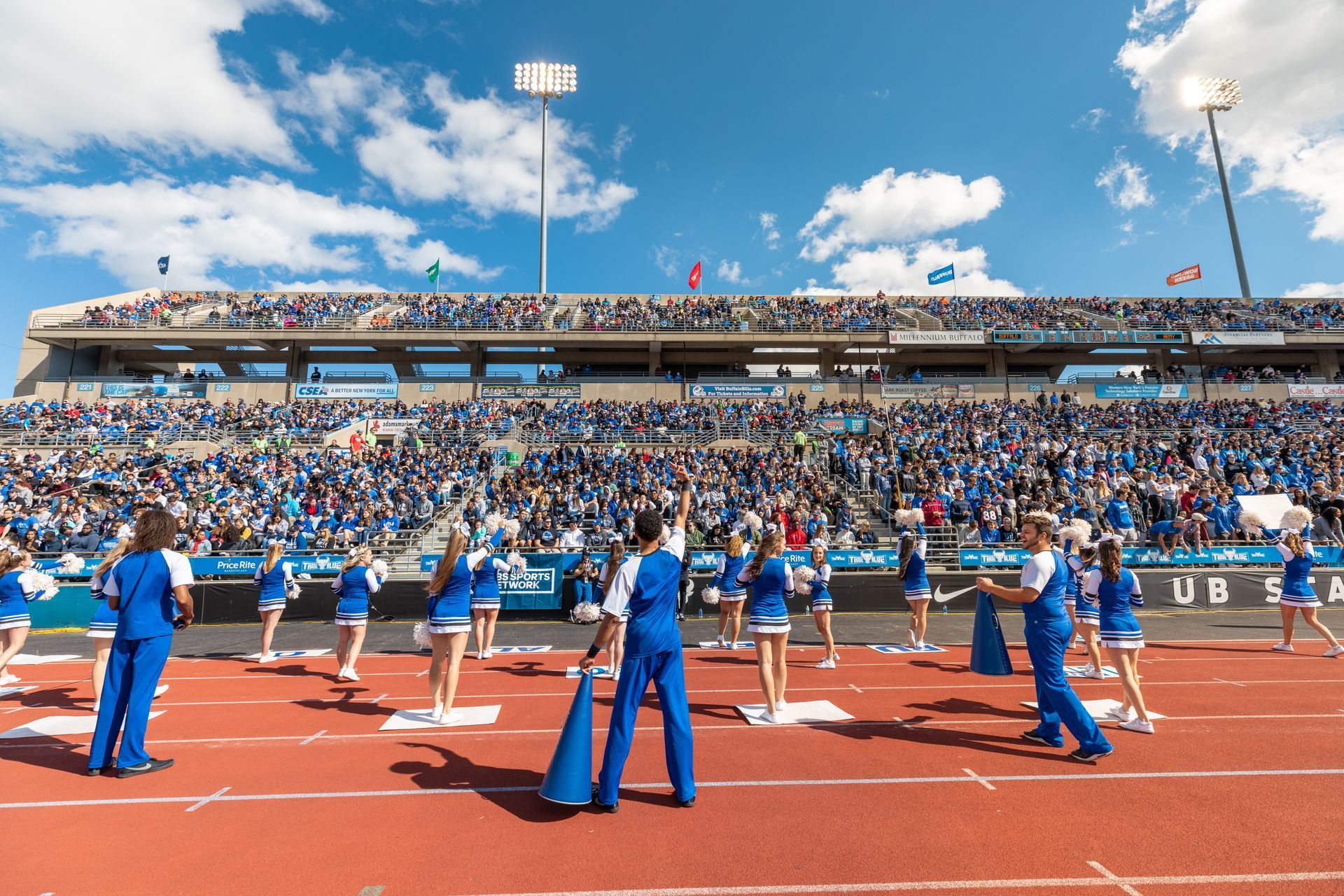 A group of cheerleaders are standing on a track in a stadium.