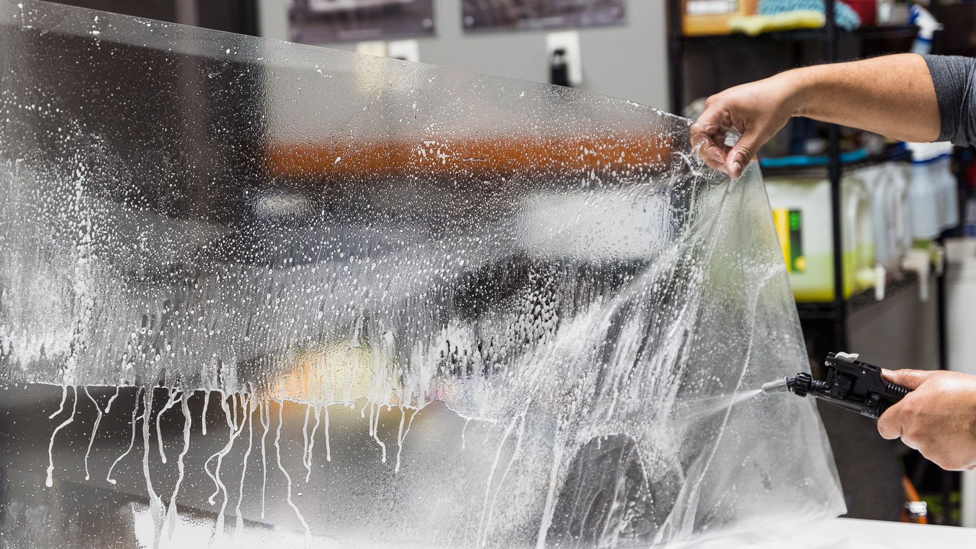 A person is spraying water on a window with a spray bottle.