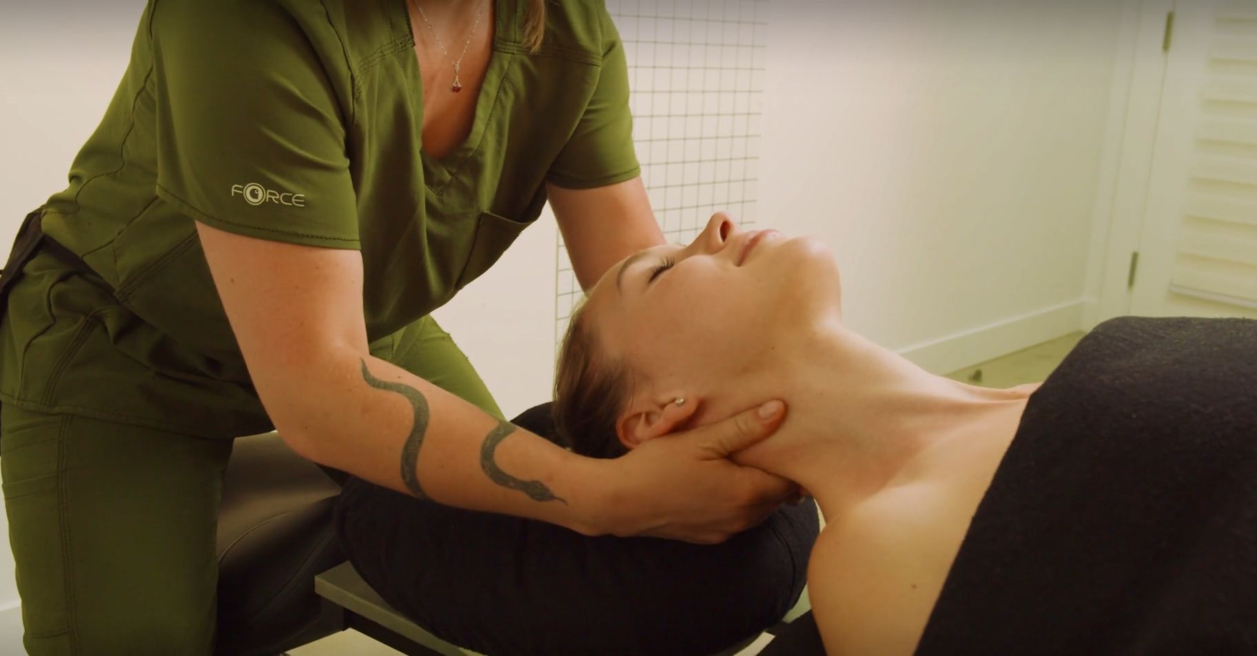 Une femme est allongée sur une table et reçoit un massage d'un massothérapeute.