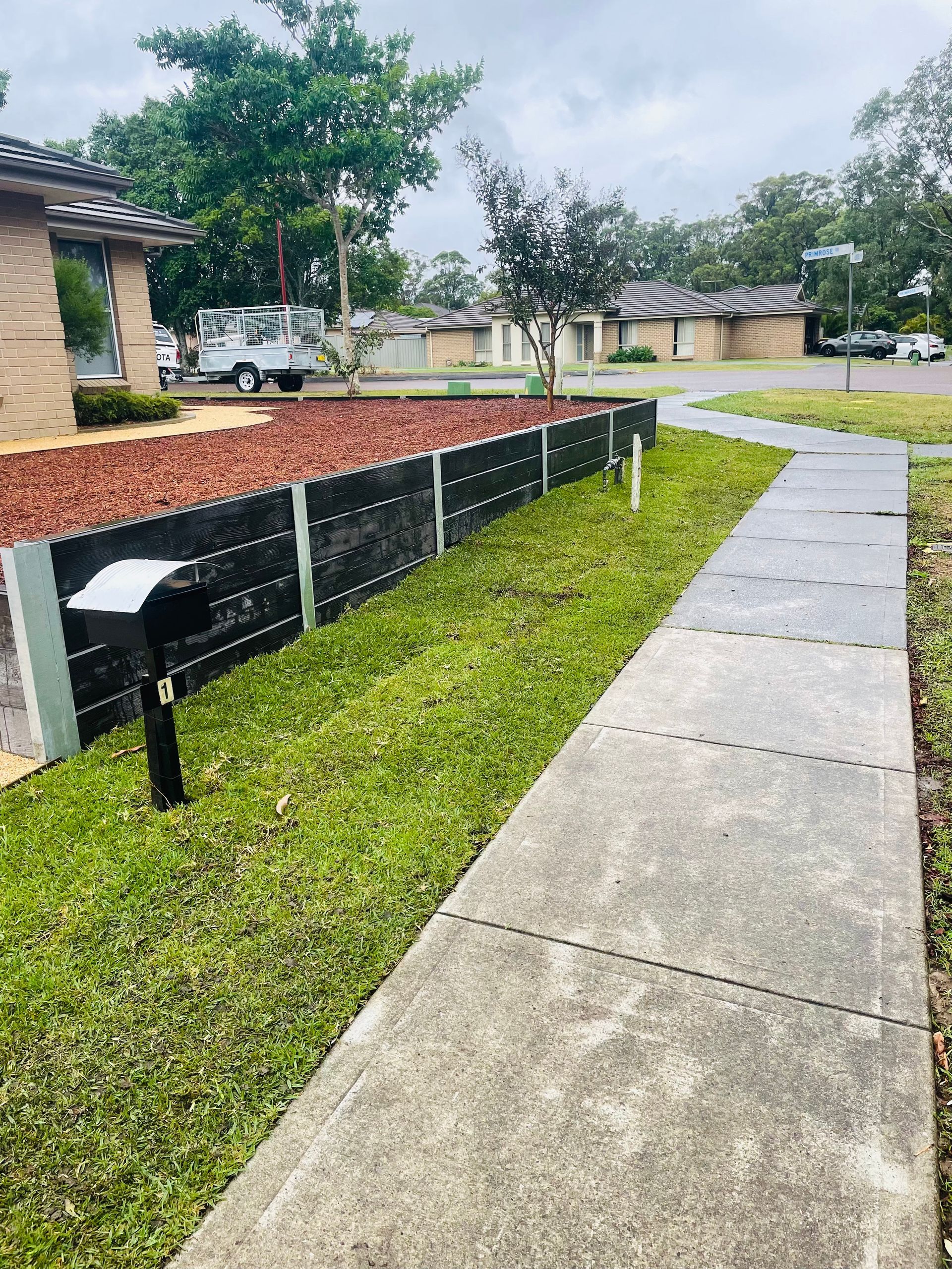 A concrete walkway leading to a house in a residential area.