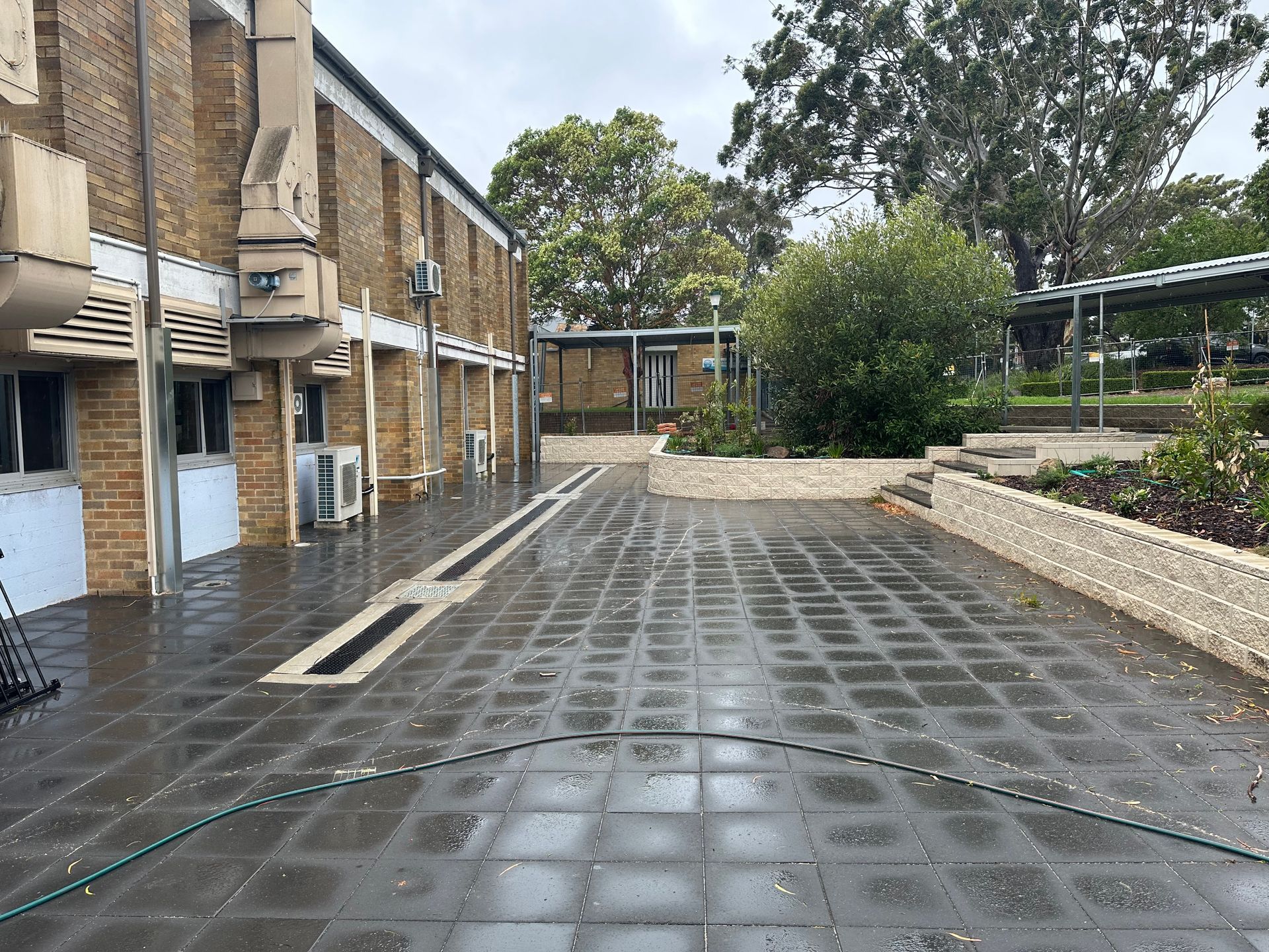 A hose is being used to clean the sidewalk in front of a building.