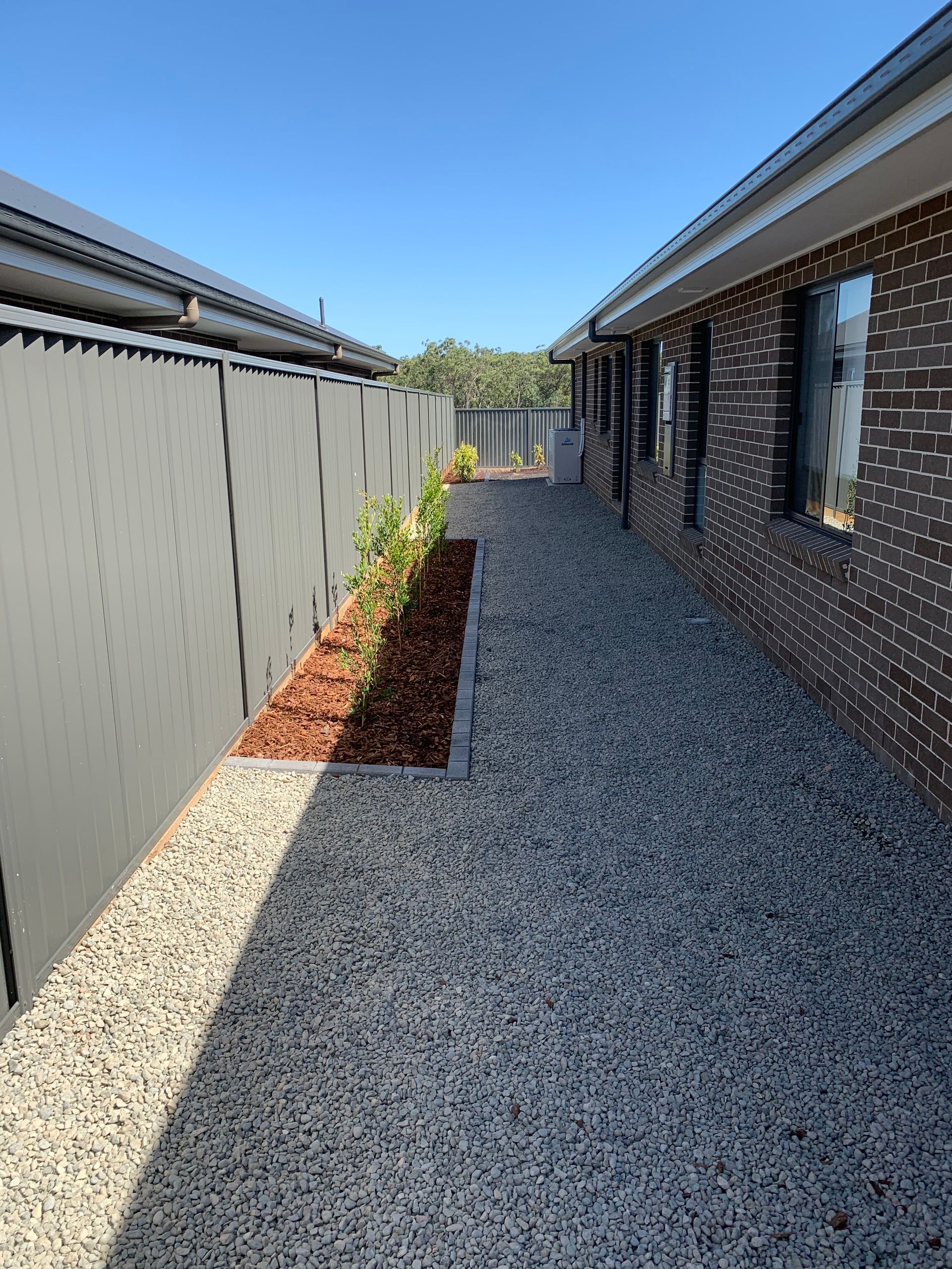 A brick house with a gravel walkway leading to it.