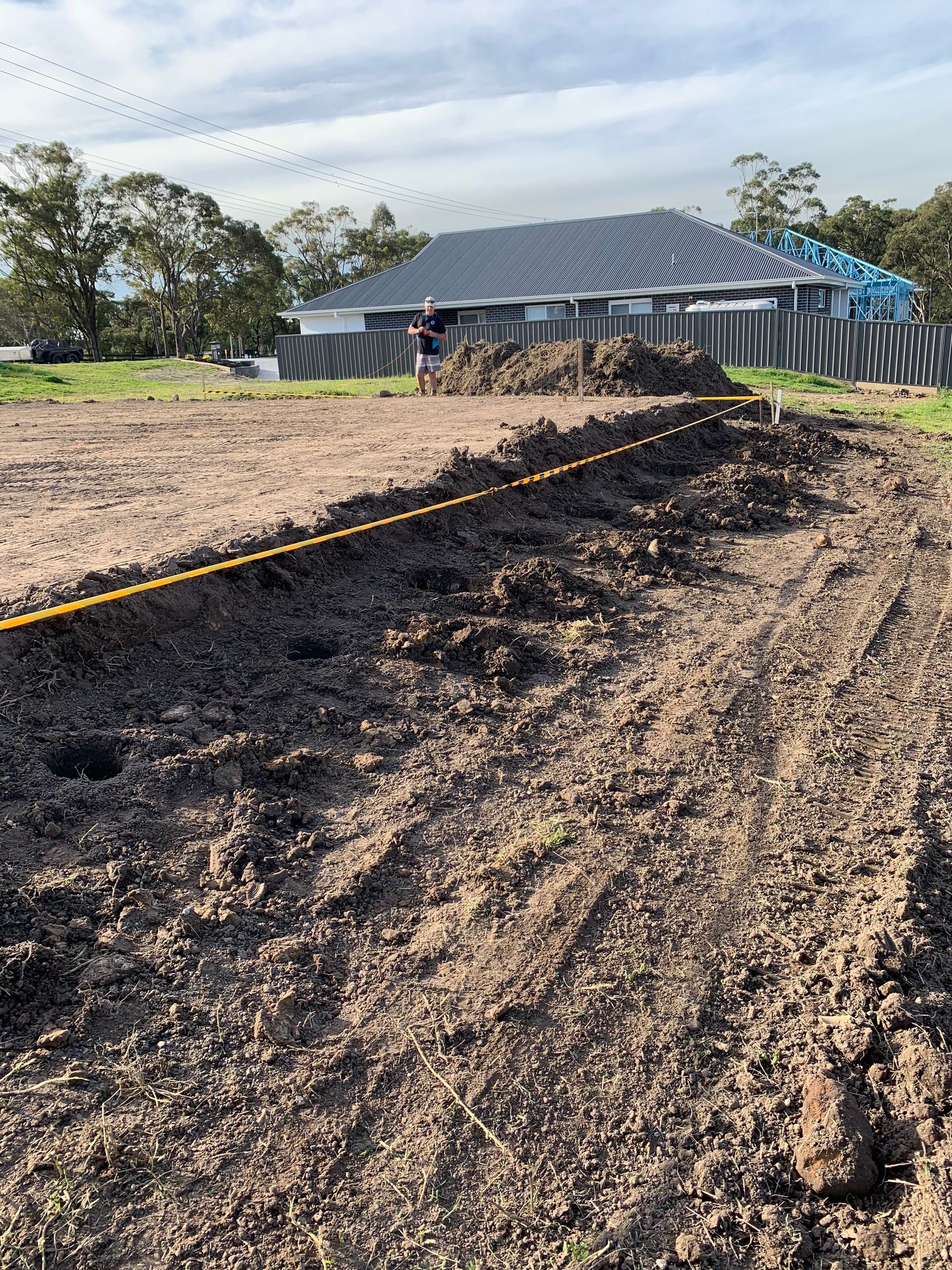 A dirt field with a house in the background.