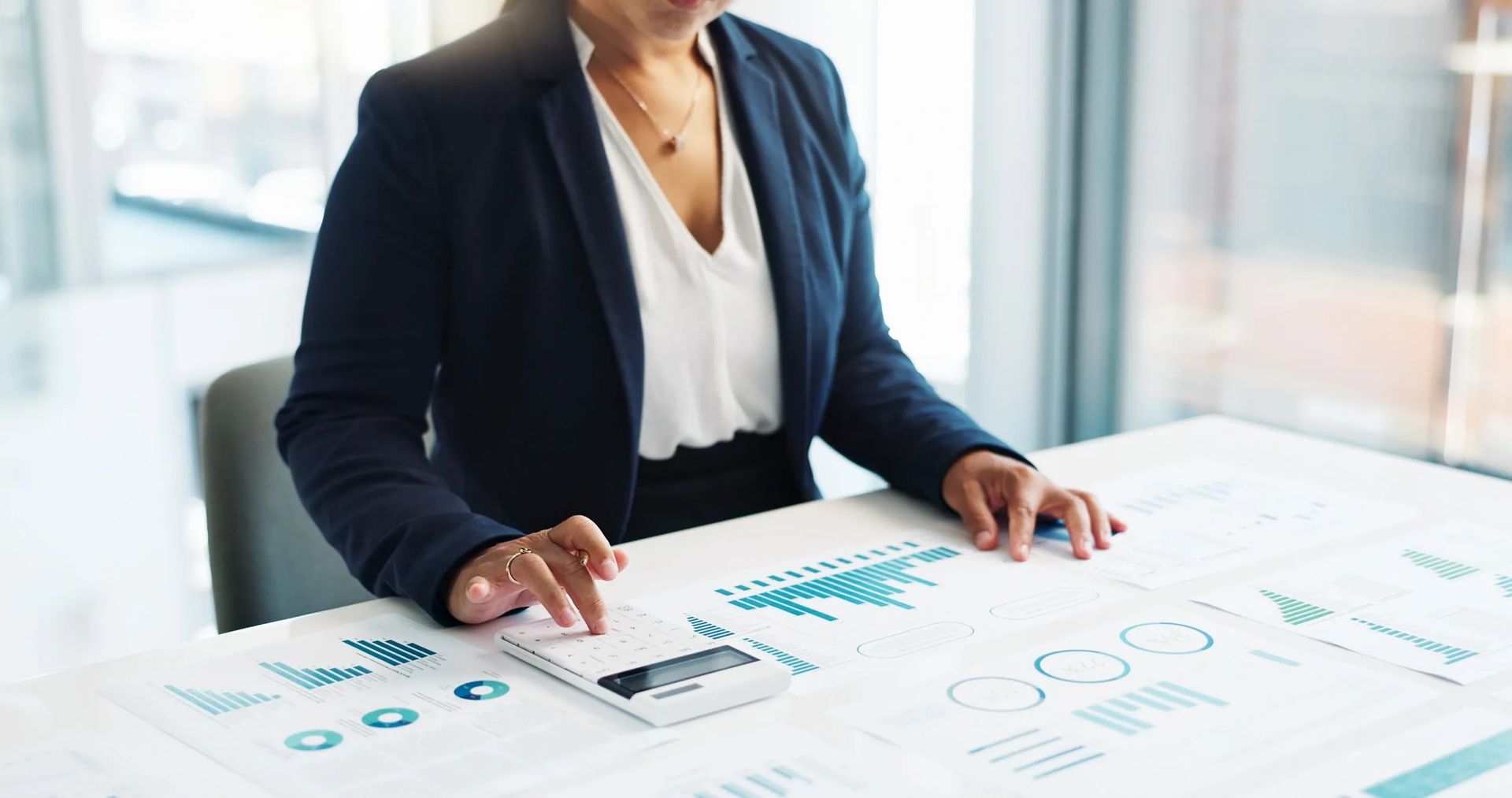 A woman is sitting at a table with a laptop and a calculator.