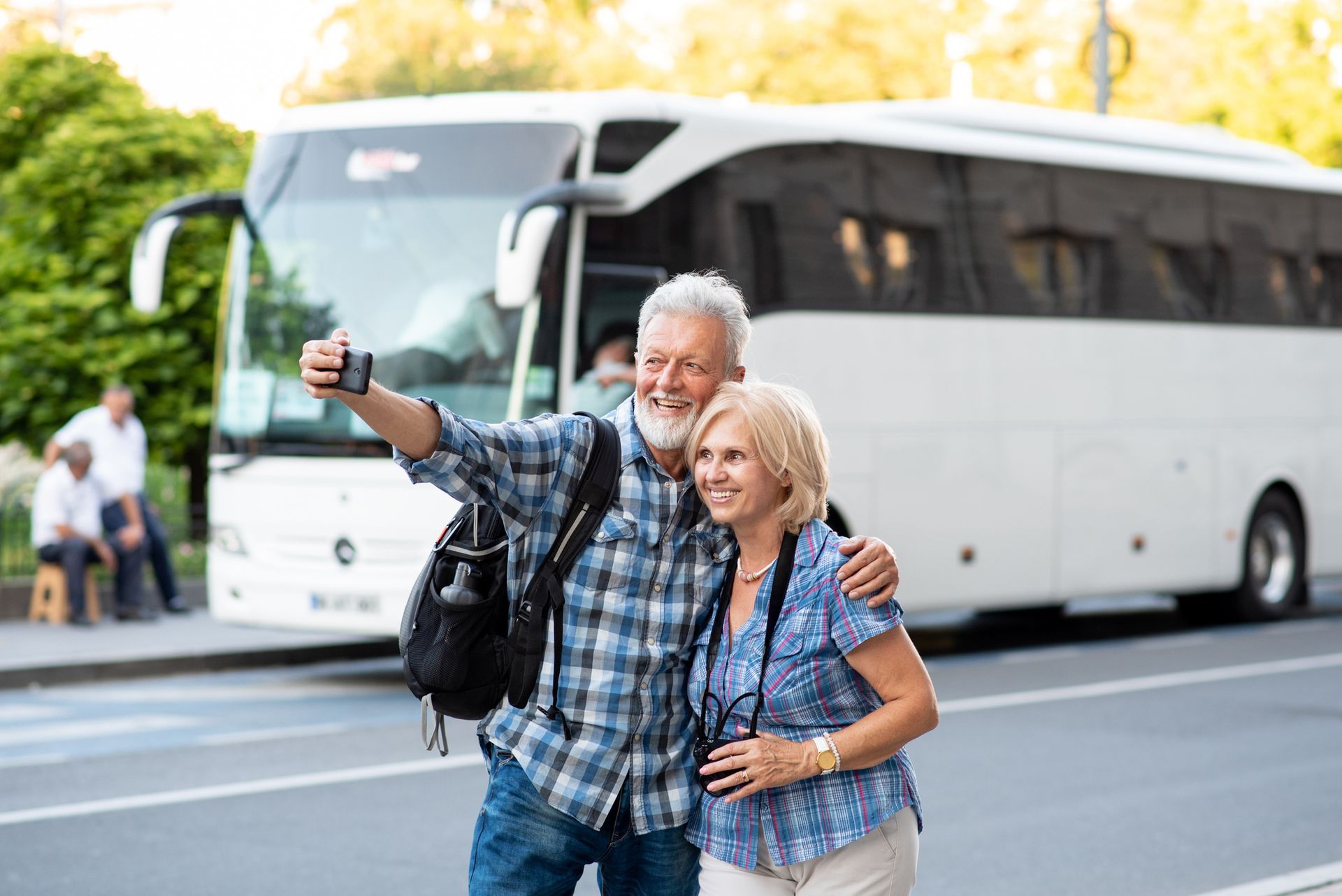Een ouder echtpaar maakt een selfie voor een bus.