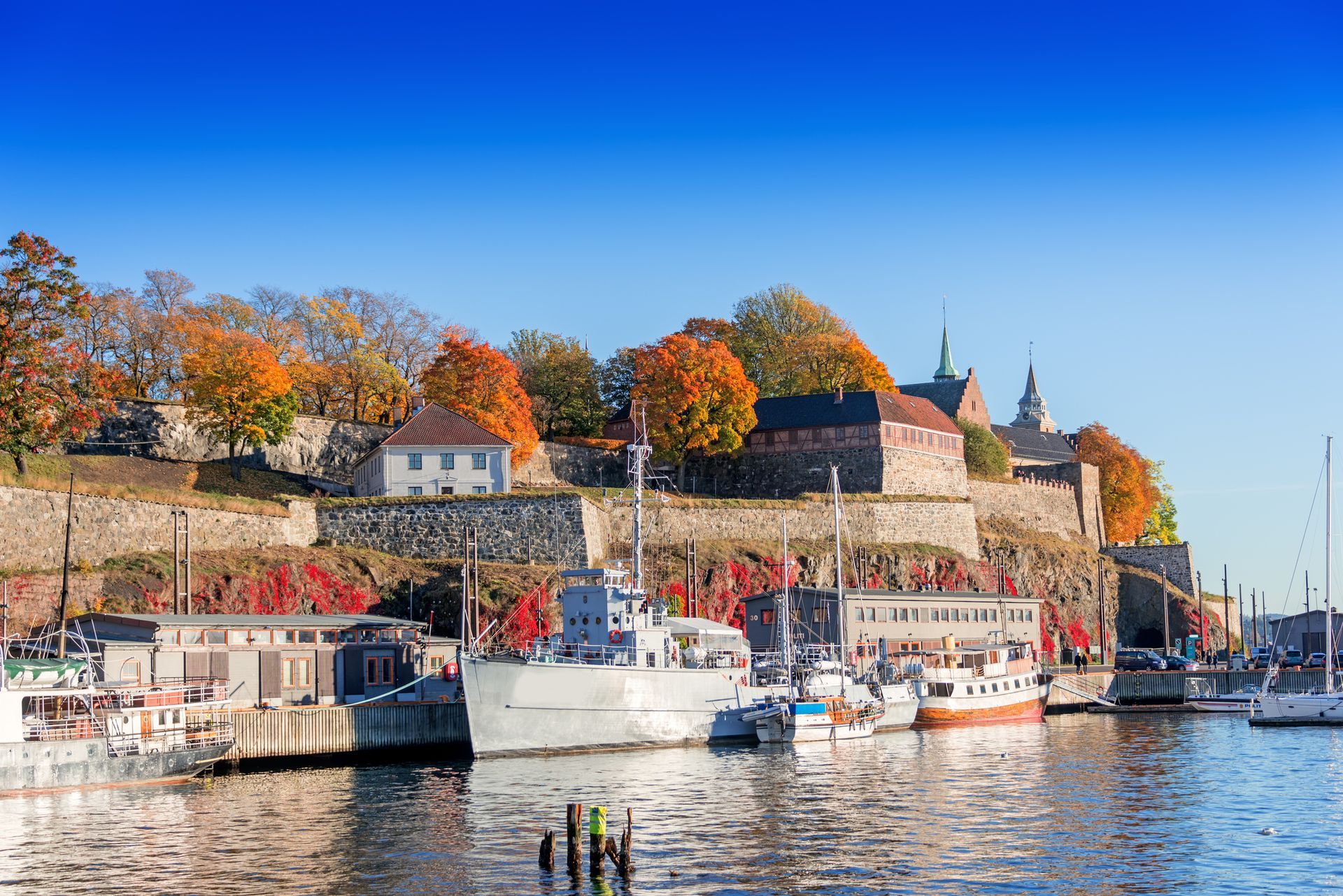 Uitzicht op het water van het fort Akershus in Oslo, Noorwegen, tijdens de herfst; boten aangemeerd in de haven.