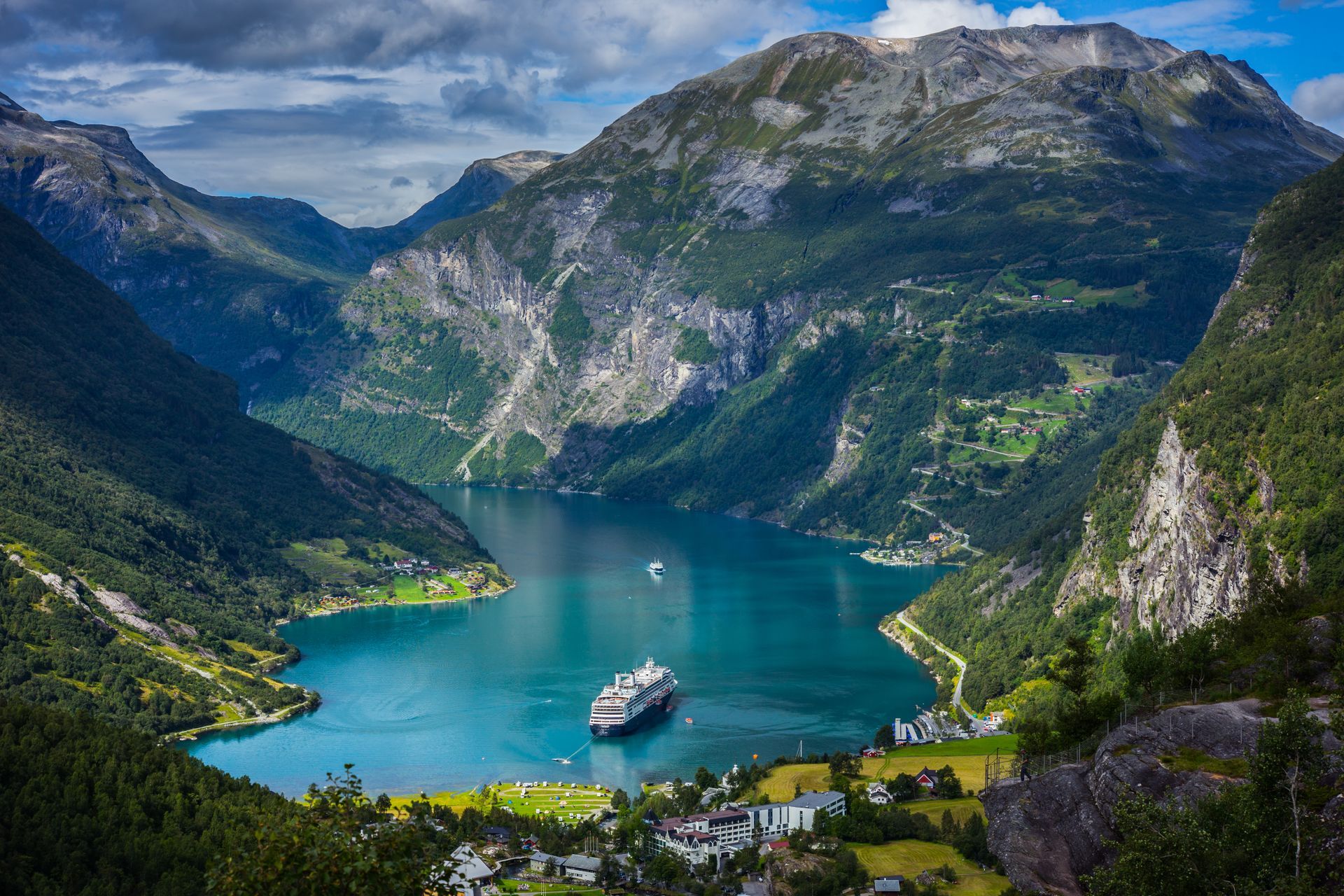 Een cruiseschip drijft op het Geirangerfjord omgeven door bergen.