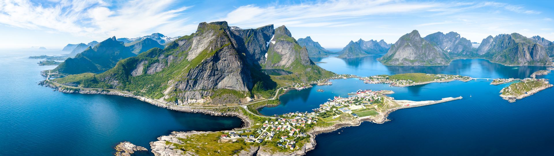 Een luchtfoto van een eiland in de oceaan, omgeven door bergen.