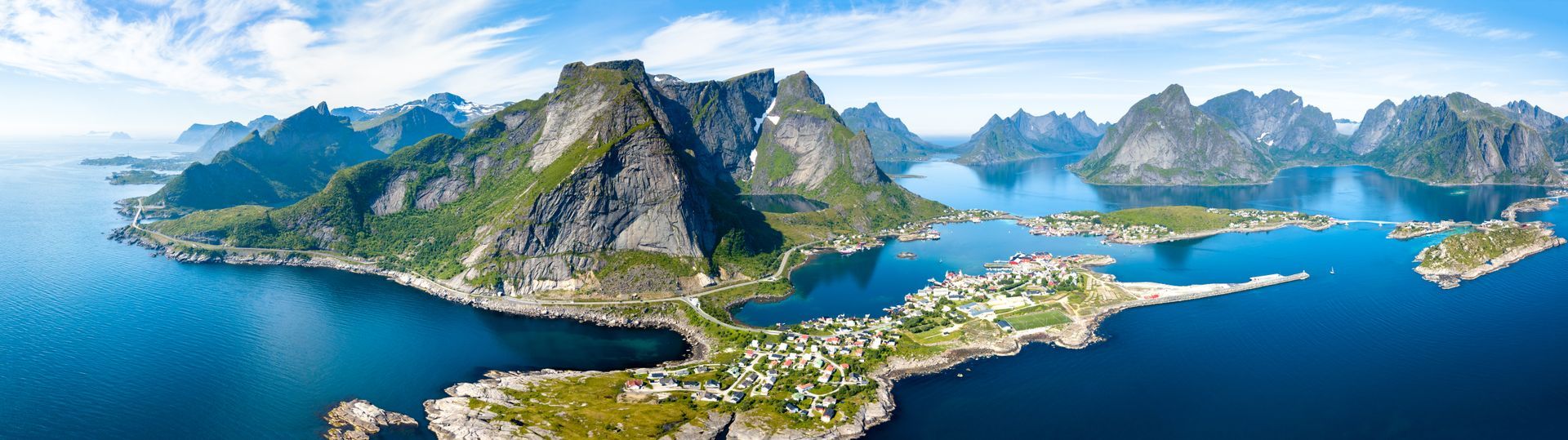 Een luchtfoto van een klein eiland in het midden van een groot wateroppervlak, omgeven door bergen.