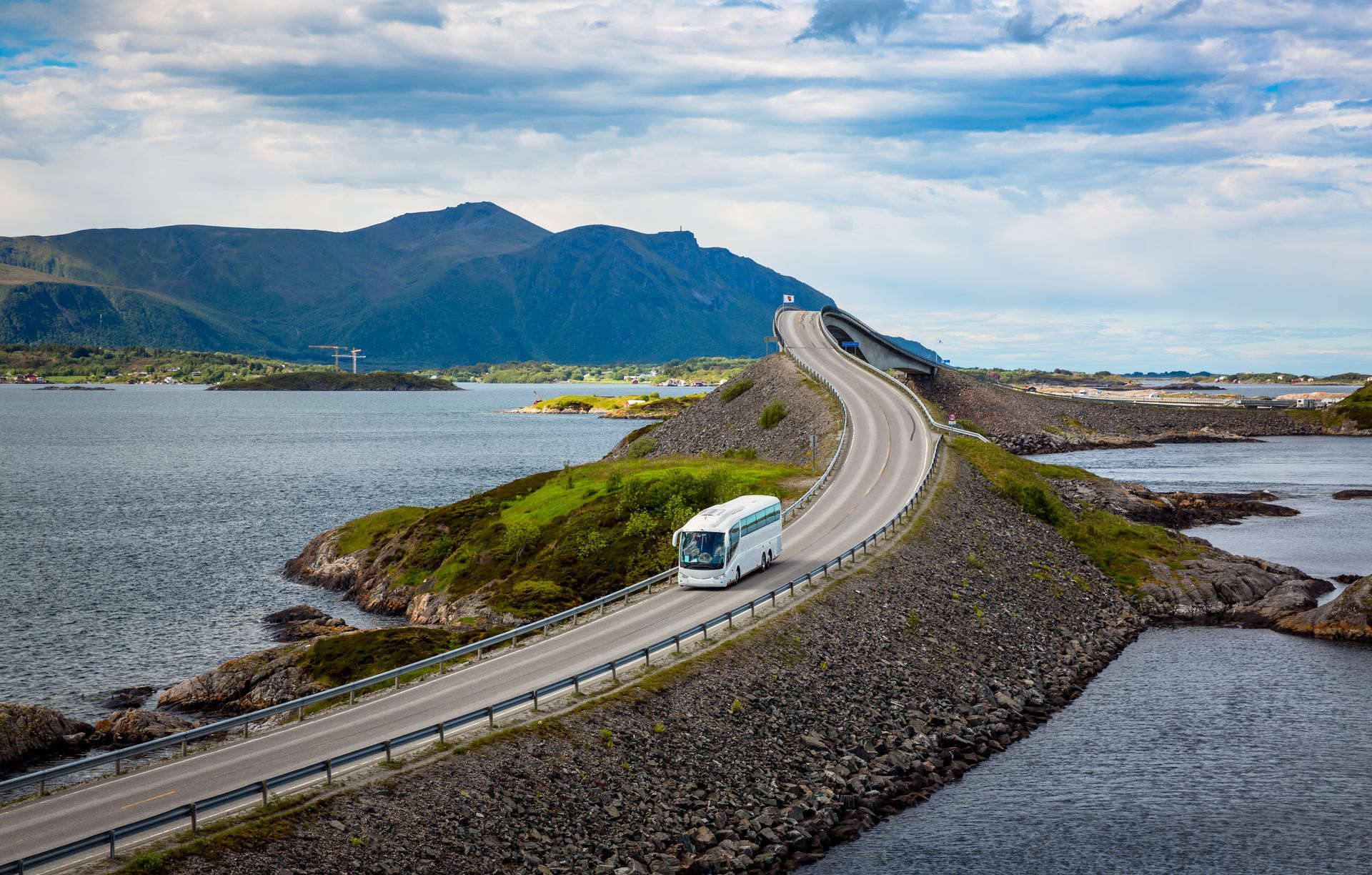 Een witte bus rijdt over de Atlantic Road omringt door de oceaan.