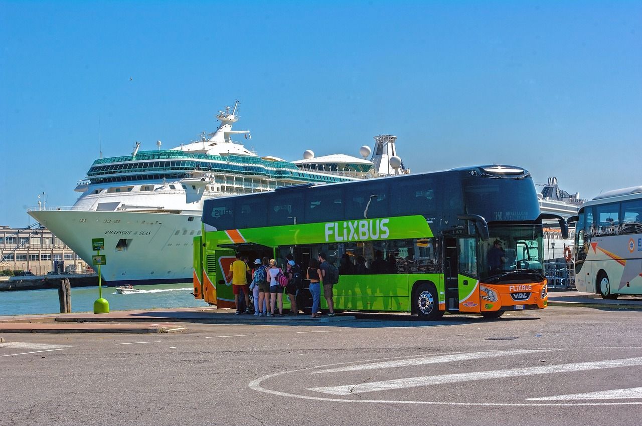 Een groen-oranje bus staat geparkeerd voor een cruiseschip.