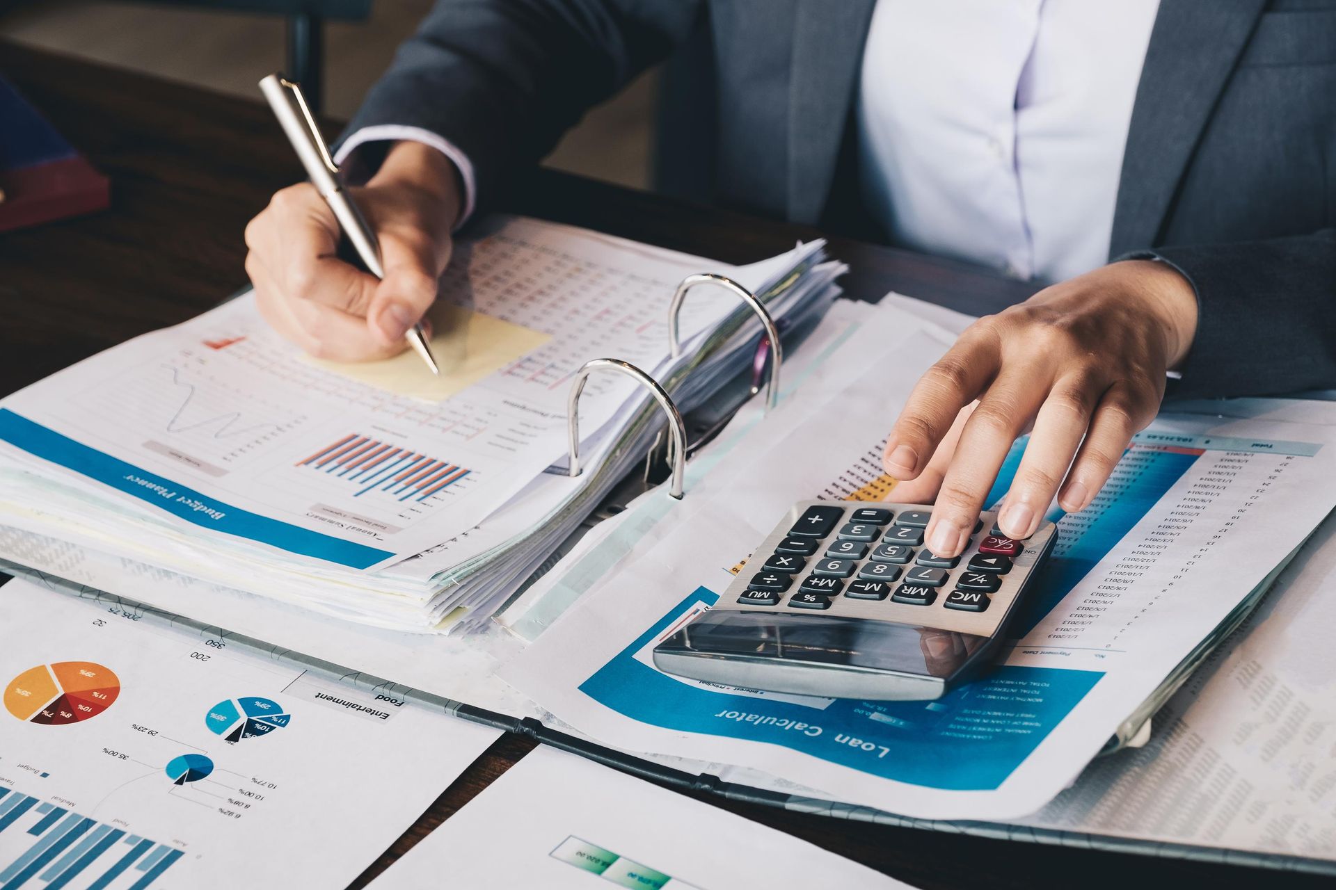 A woman is using a calculator and writing on a piece of paper.