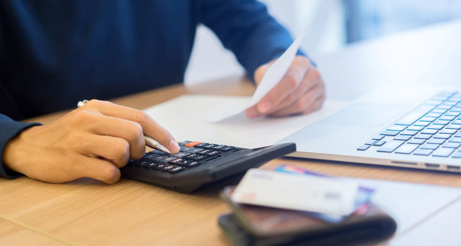 A person is using a calculator and writing on a piece of paper.