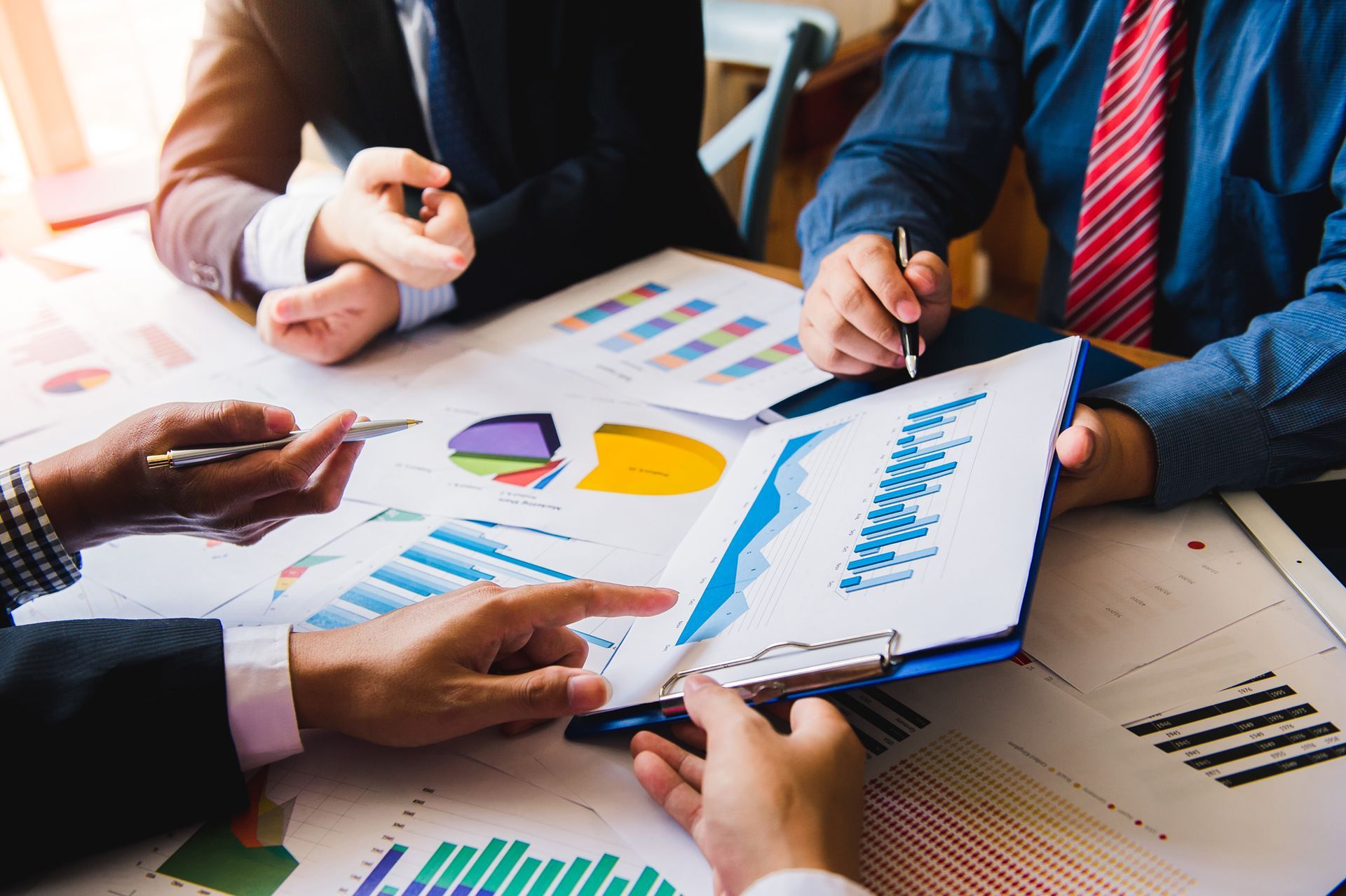A group of business people are sitting around a table looking at charts and graphs.