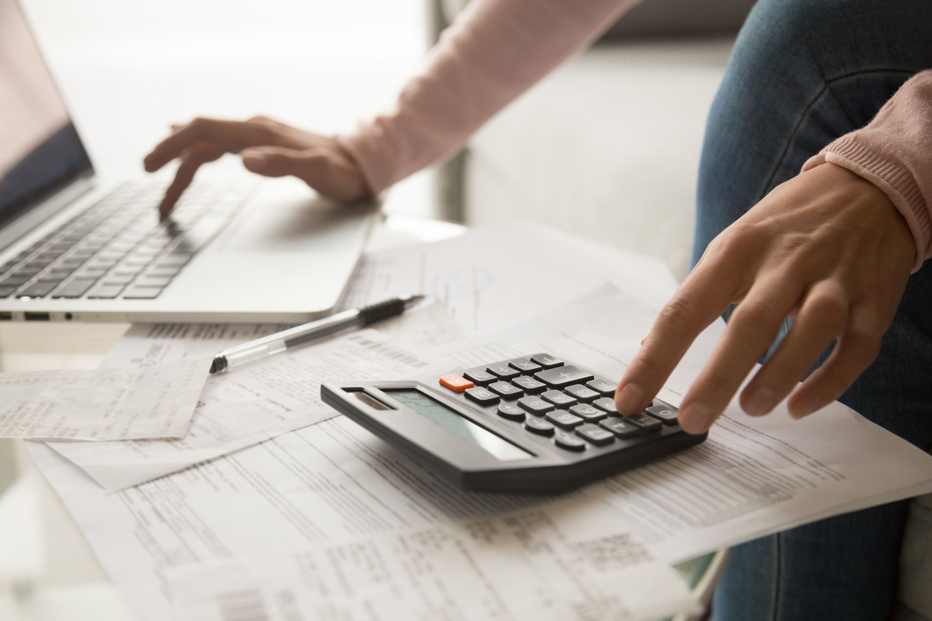 A woman is using a laptop and a calculator at the same time.