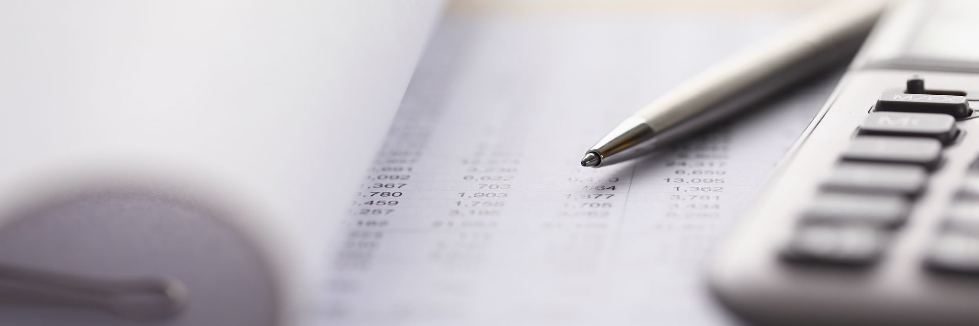 A pen is sitting on top of a piece of paper next to a calculator.