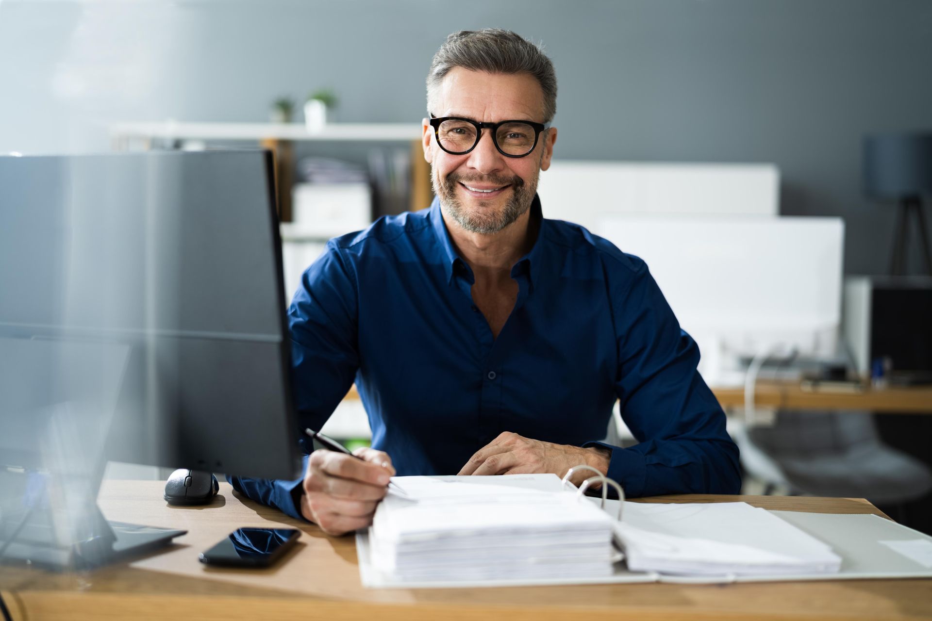 A man is sitting at a desk in front of a computer.