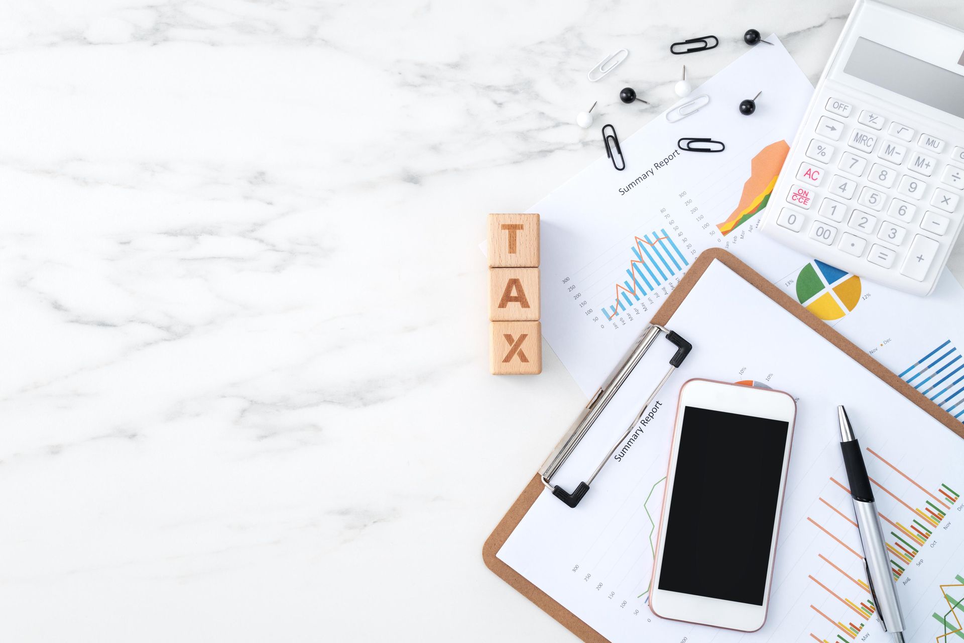 A wooden block with the word tax written on it is sitting on top of a clipboard.