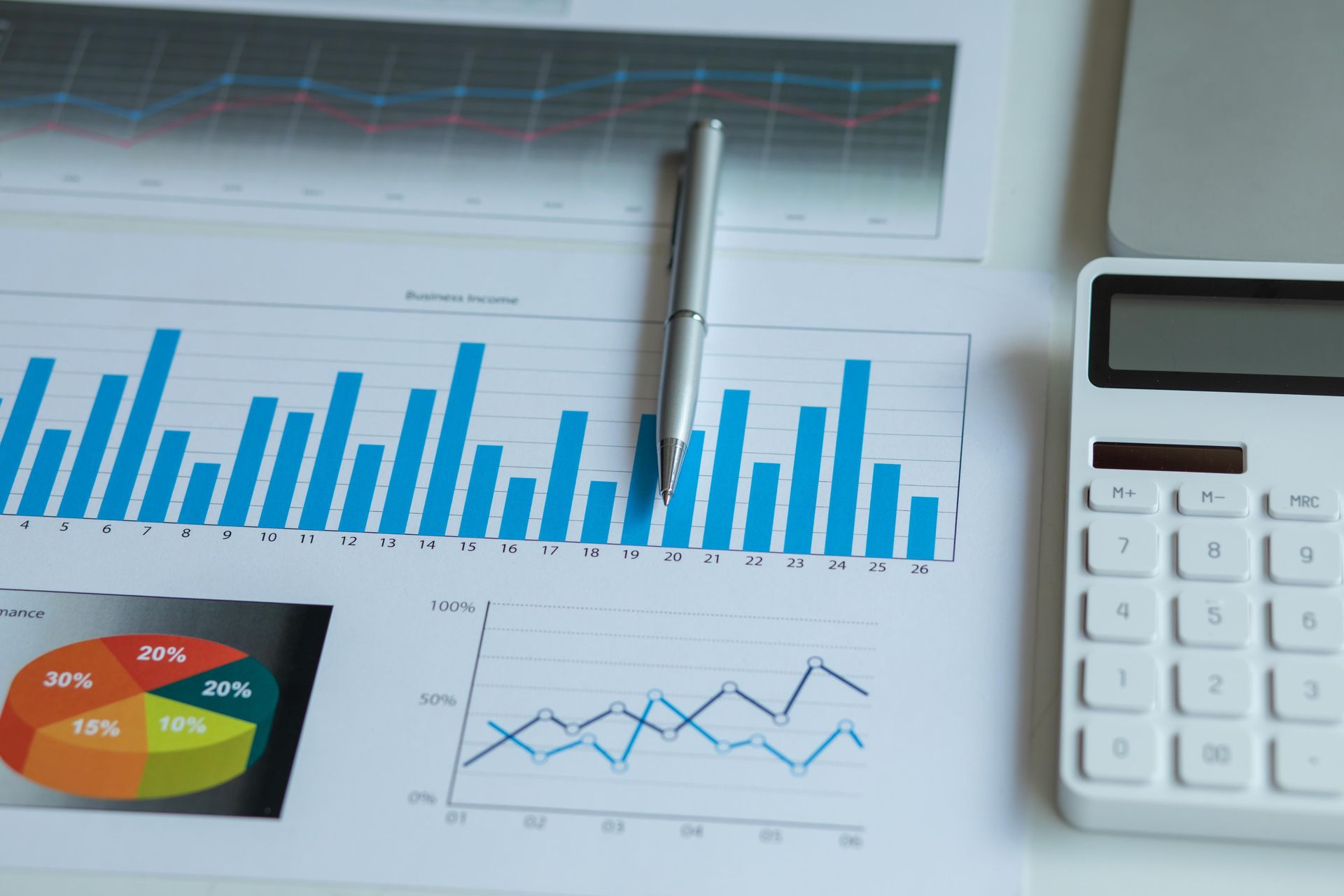 A pen is sitting on top of a graph next to a calculator.