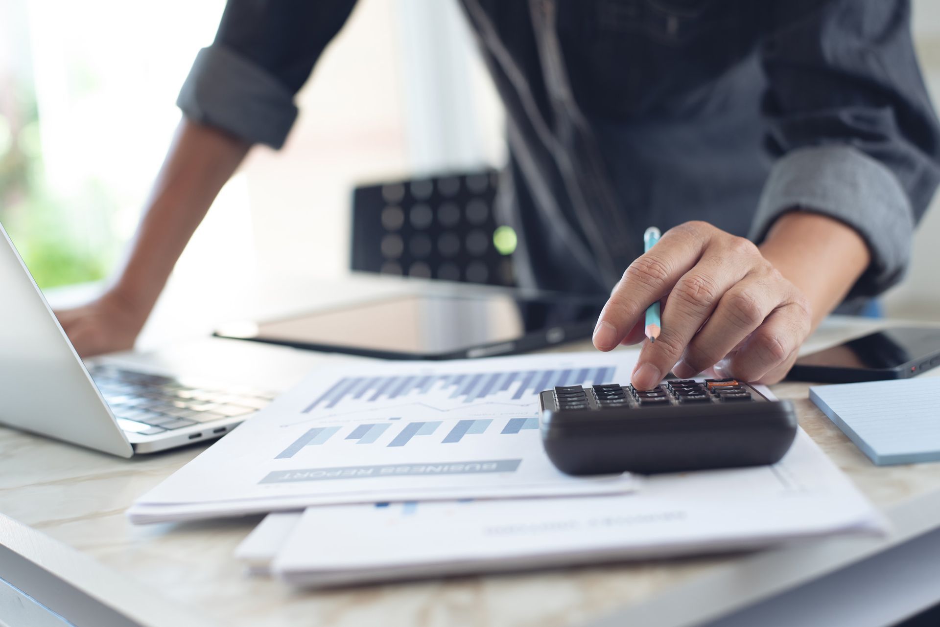 A man is using a laptop and a calculator at a desk.