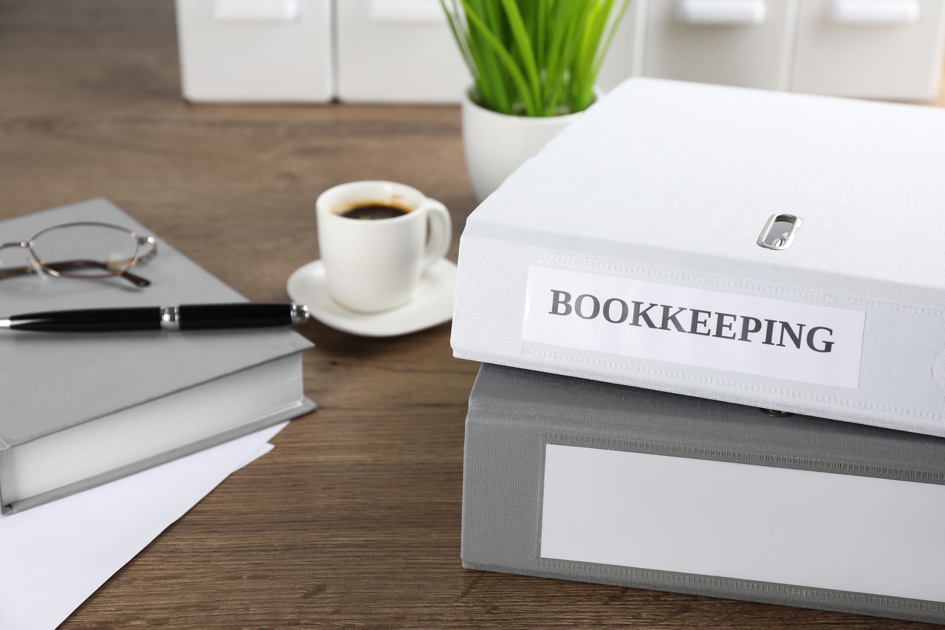 A stack of bookkeeping binders sitting on top of each other on a wooden desk.