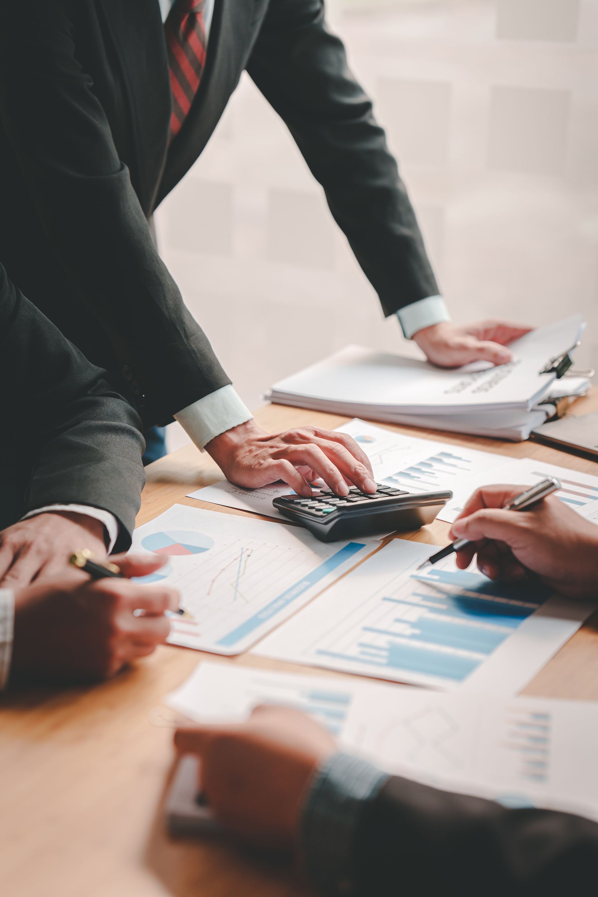 A group of business people are sitting around a table with papers and a calculator.