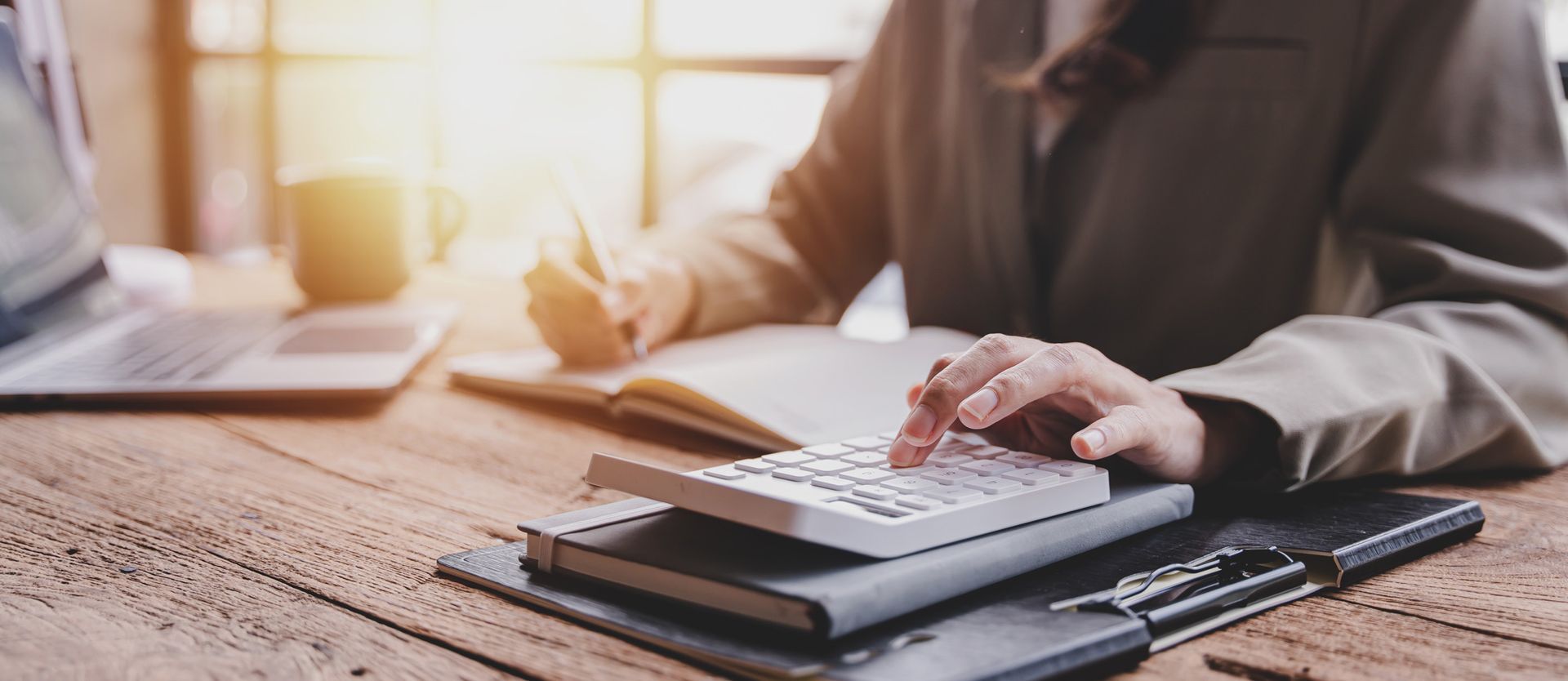 A woman is sitting at a desk using a calculator.