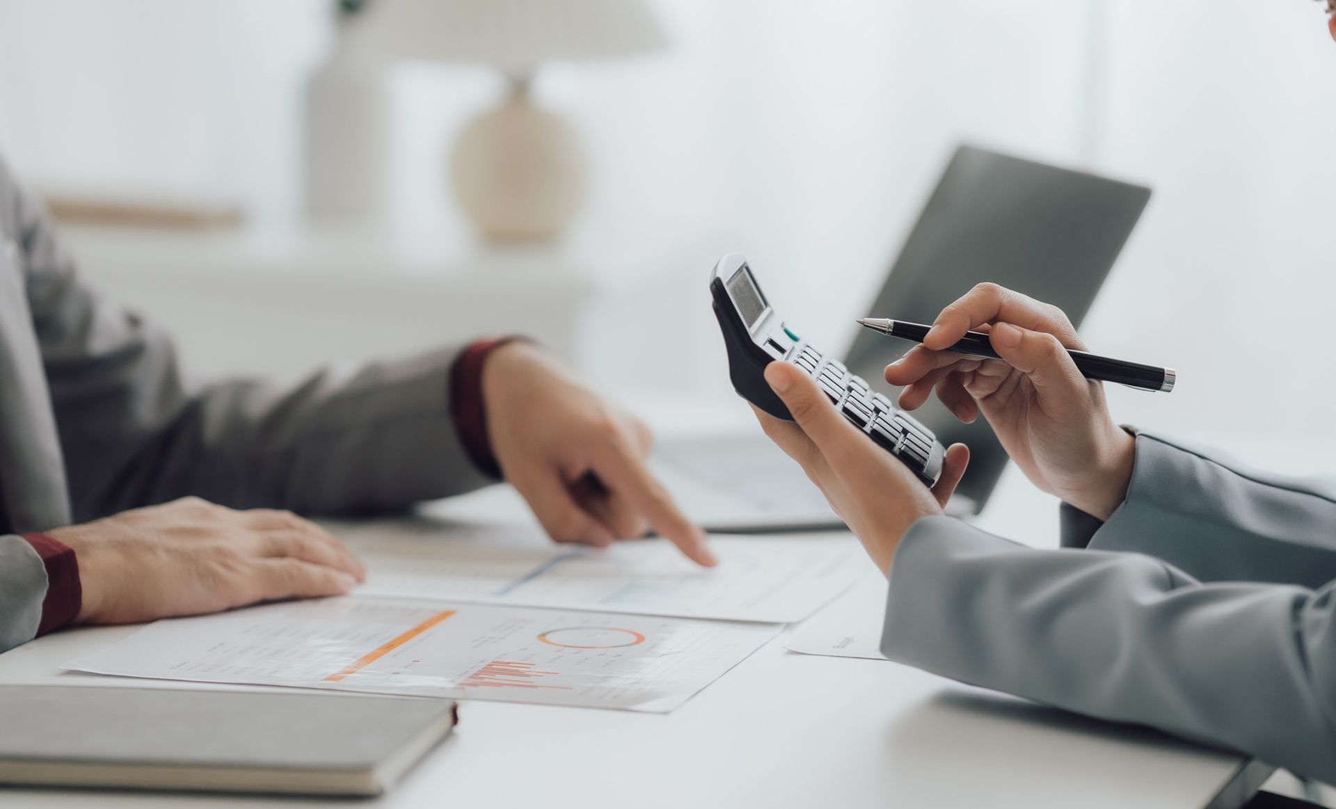 Two people are sitting at a table using a calculator.