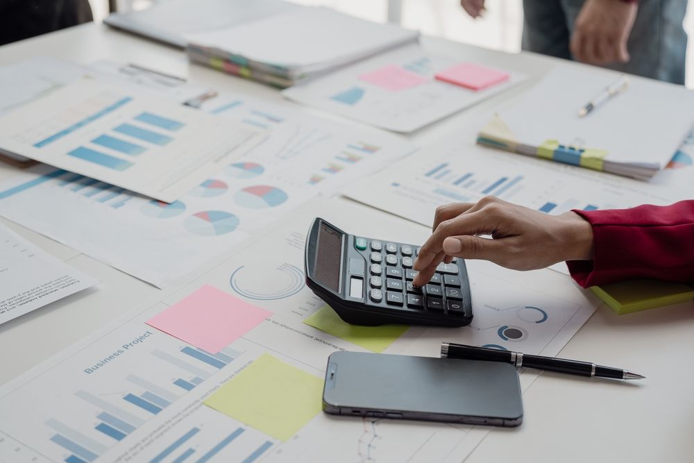A person is using a calculator on a table.