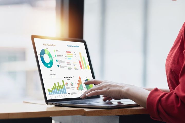 A woman is using a laptop computer with graphs on the screen.