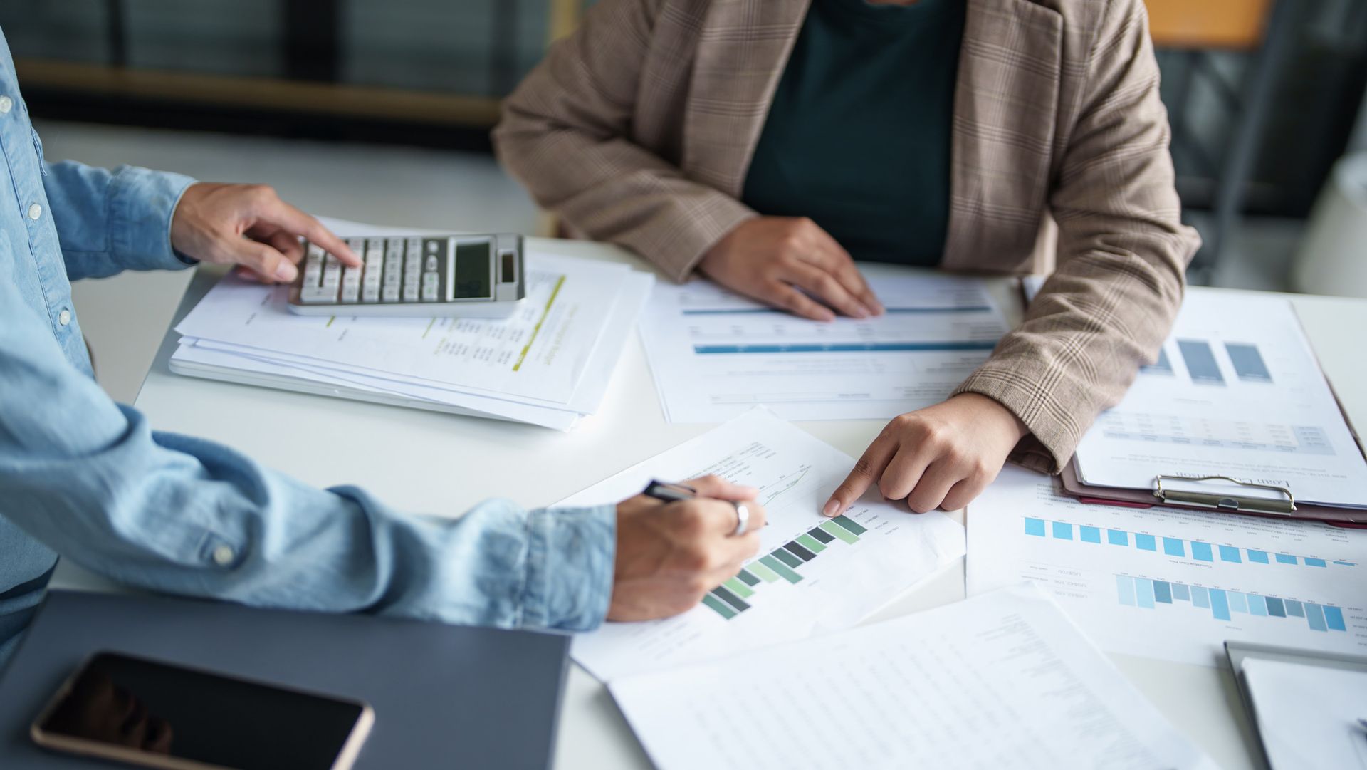 Two people are sitting at a table with papers and a calculator.