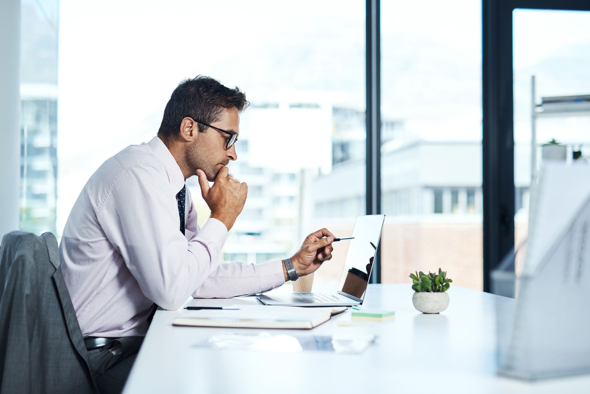 A man is sitting at a desk in front of a laptop computer.