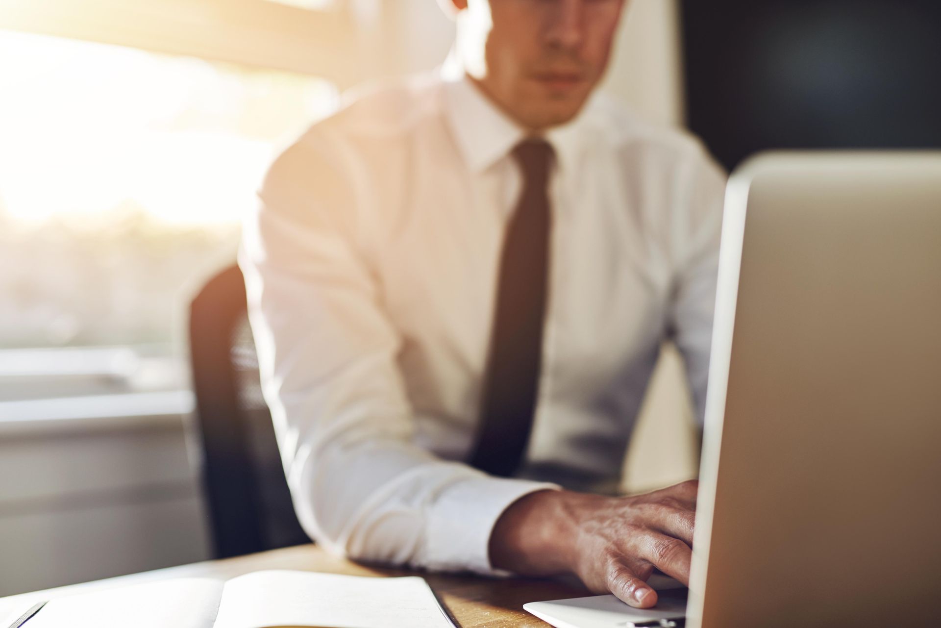 A man in a white shirt typing on a laptop computer.
