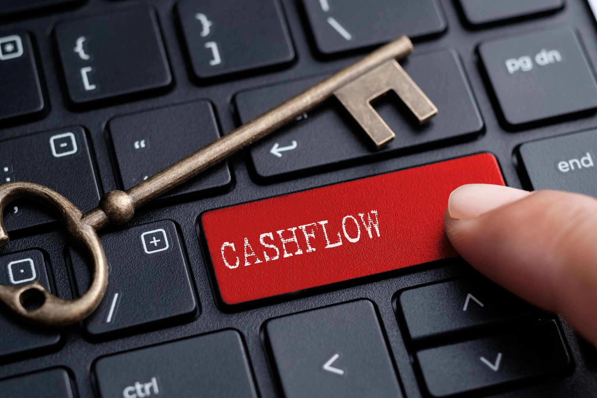 A person is pressing a red cashflow button on a keyboard.