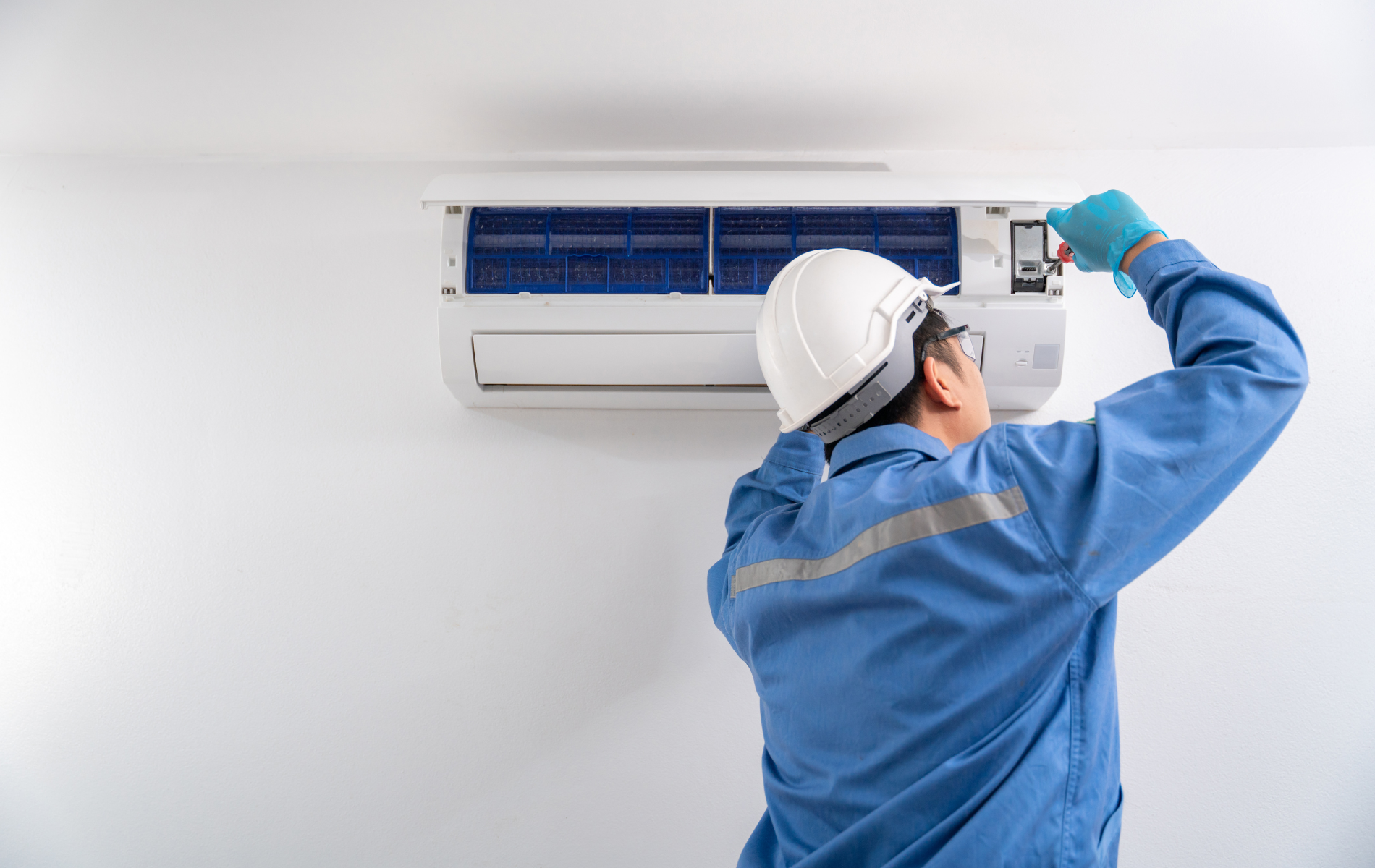 A man is working on an air conditioner in a room.