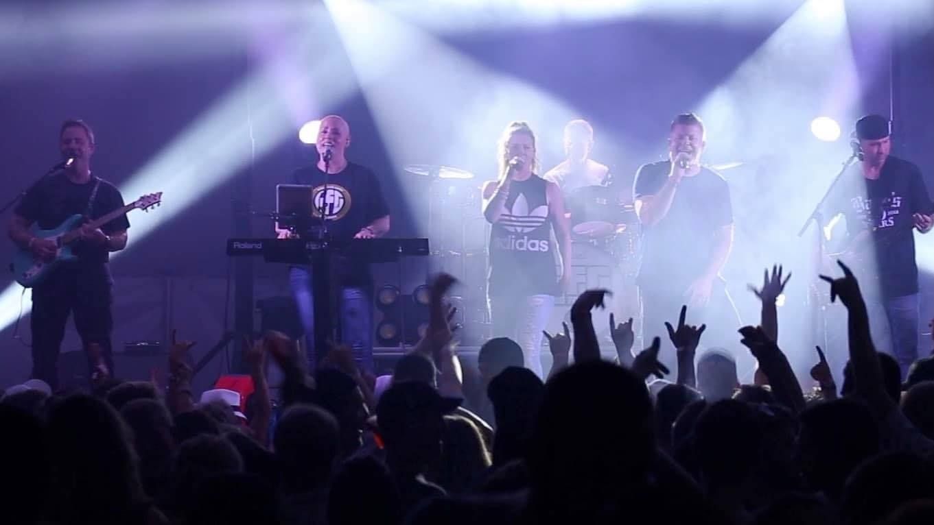 A group of people are playing instruments on a stage in front of a crowd.