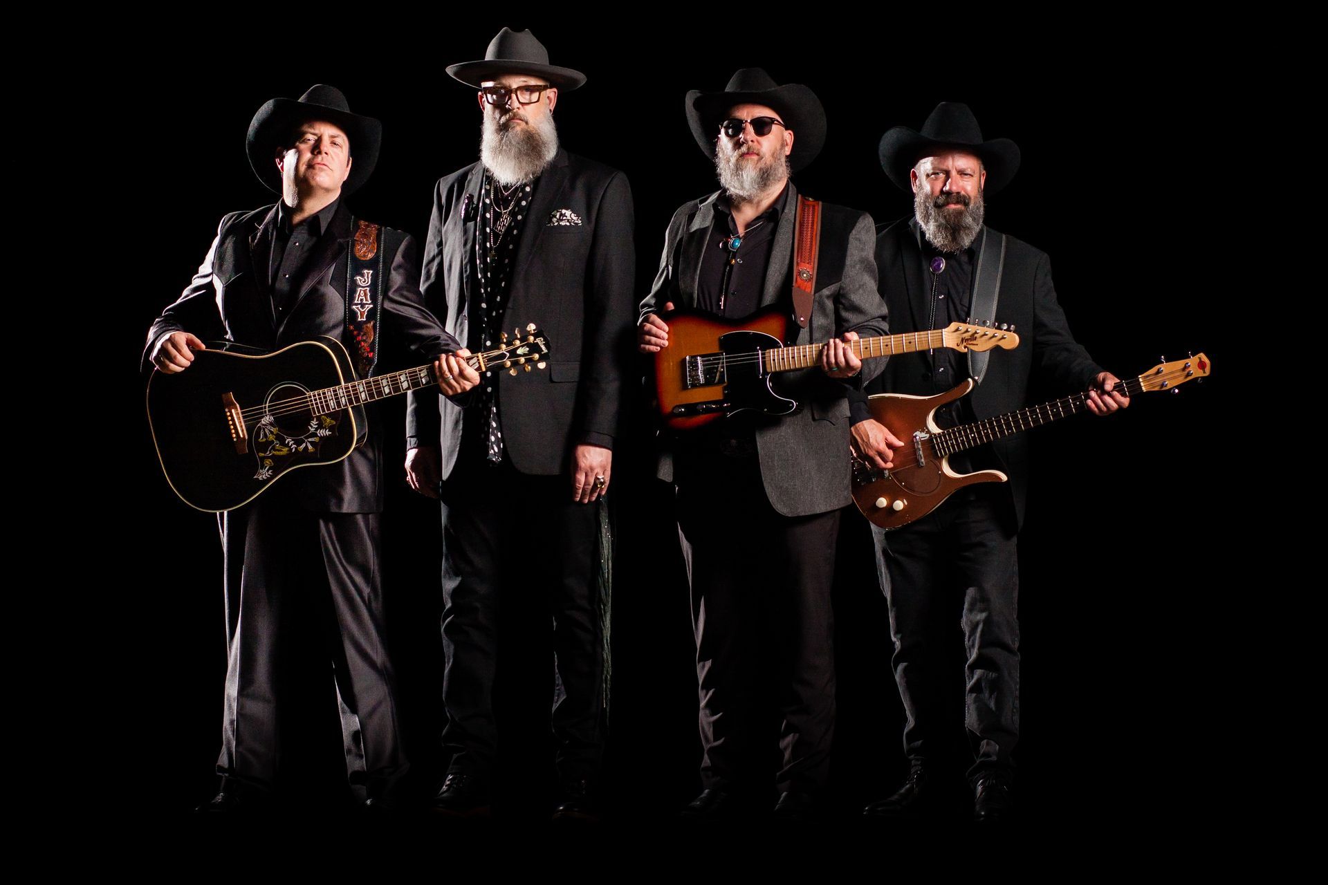 A group of men standing next to each other holding guitars.